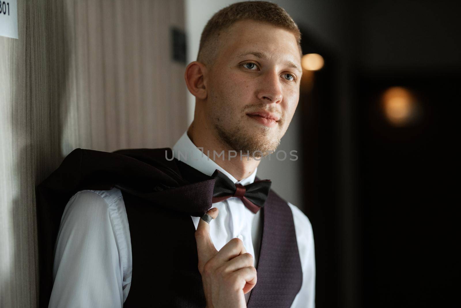 portrait of the groom in a brown three-piece suit with a bow tie on the wedding day