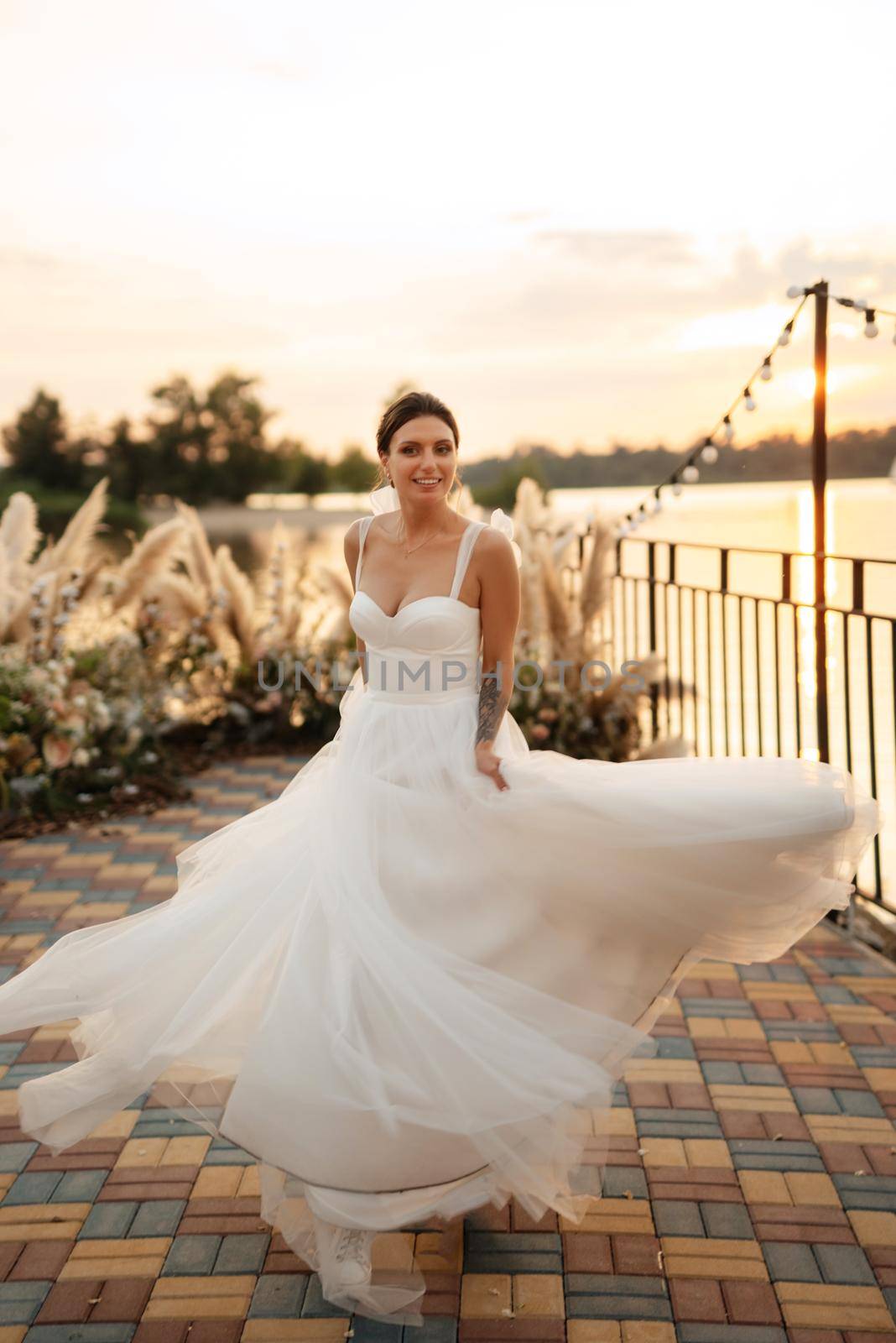 bride against the background of a yellow sunset on a pier near the river