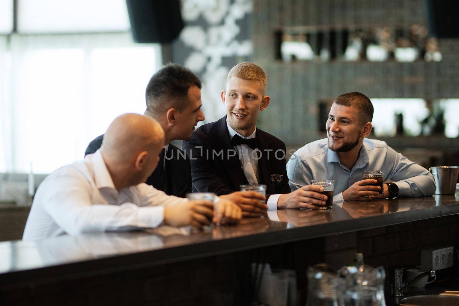 groom in a brown suit and his friends at the bar