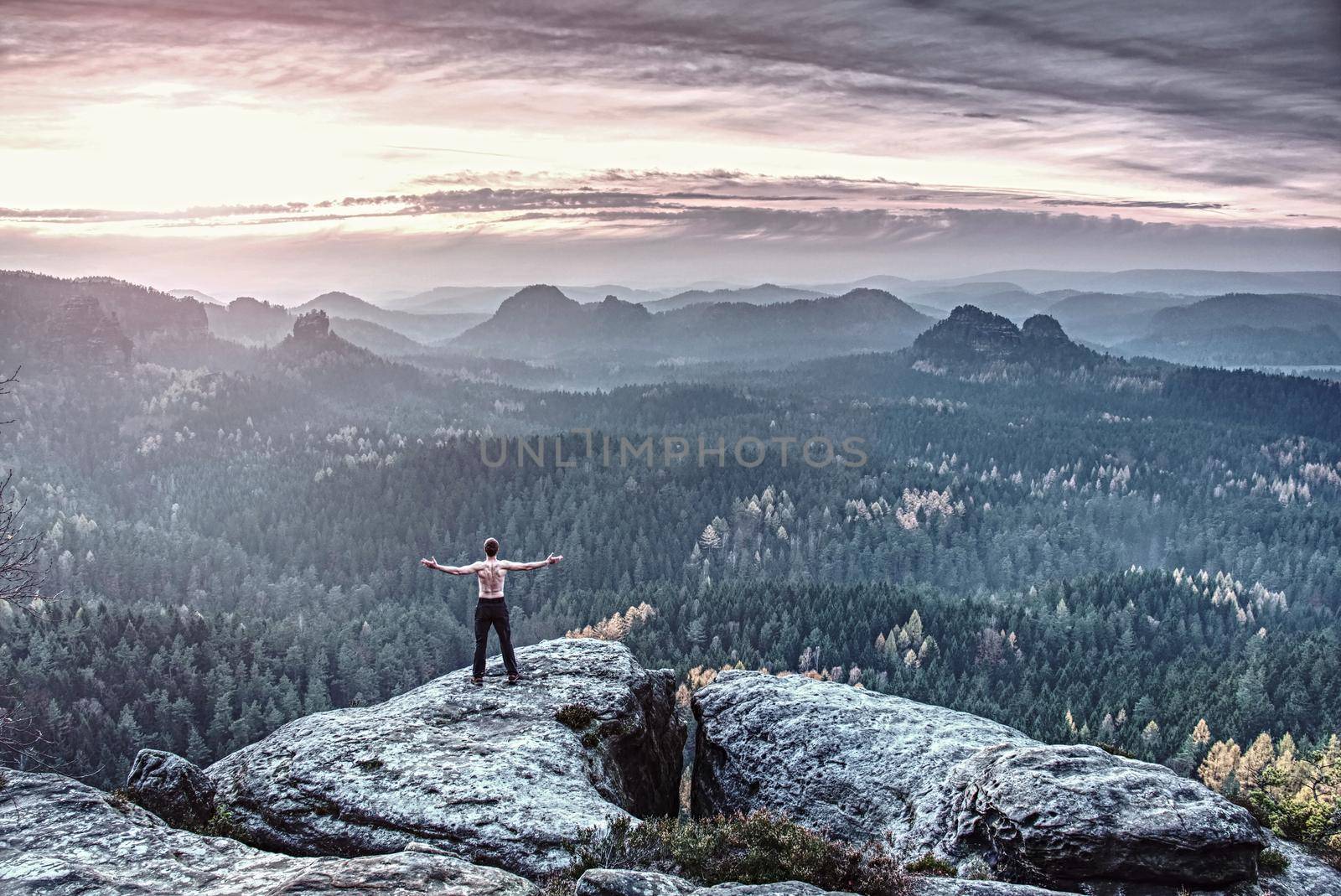 Guy on a cliff above fairy misty valley. Cracked Rock, the most famous tourist attraction.