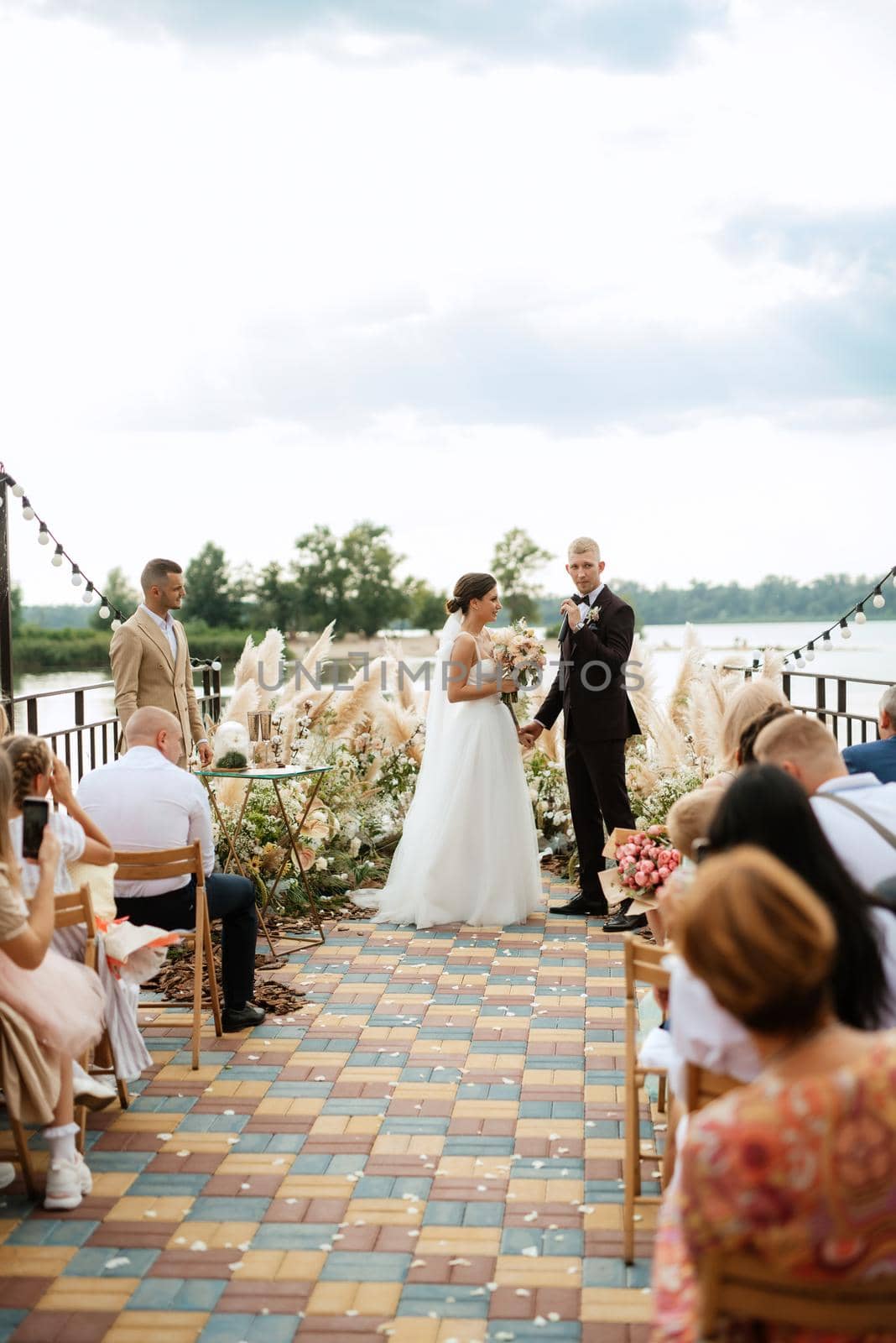 wedding ceremony on a high pier near the river with invited guests