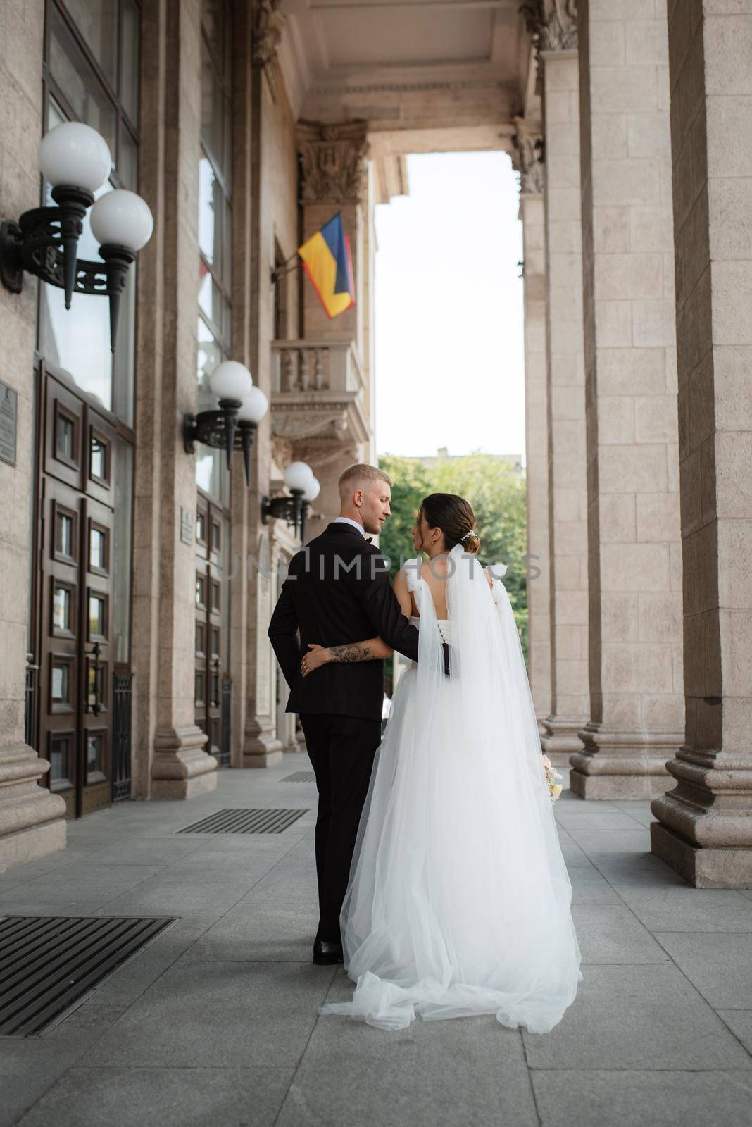 the groom in a brown suit and the bride in a white dress in an urban atmosphere