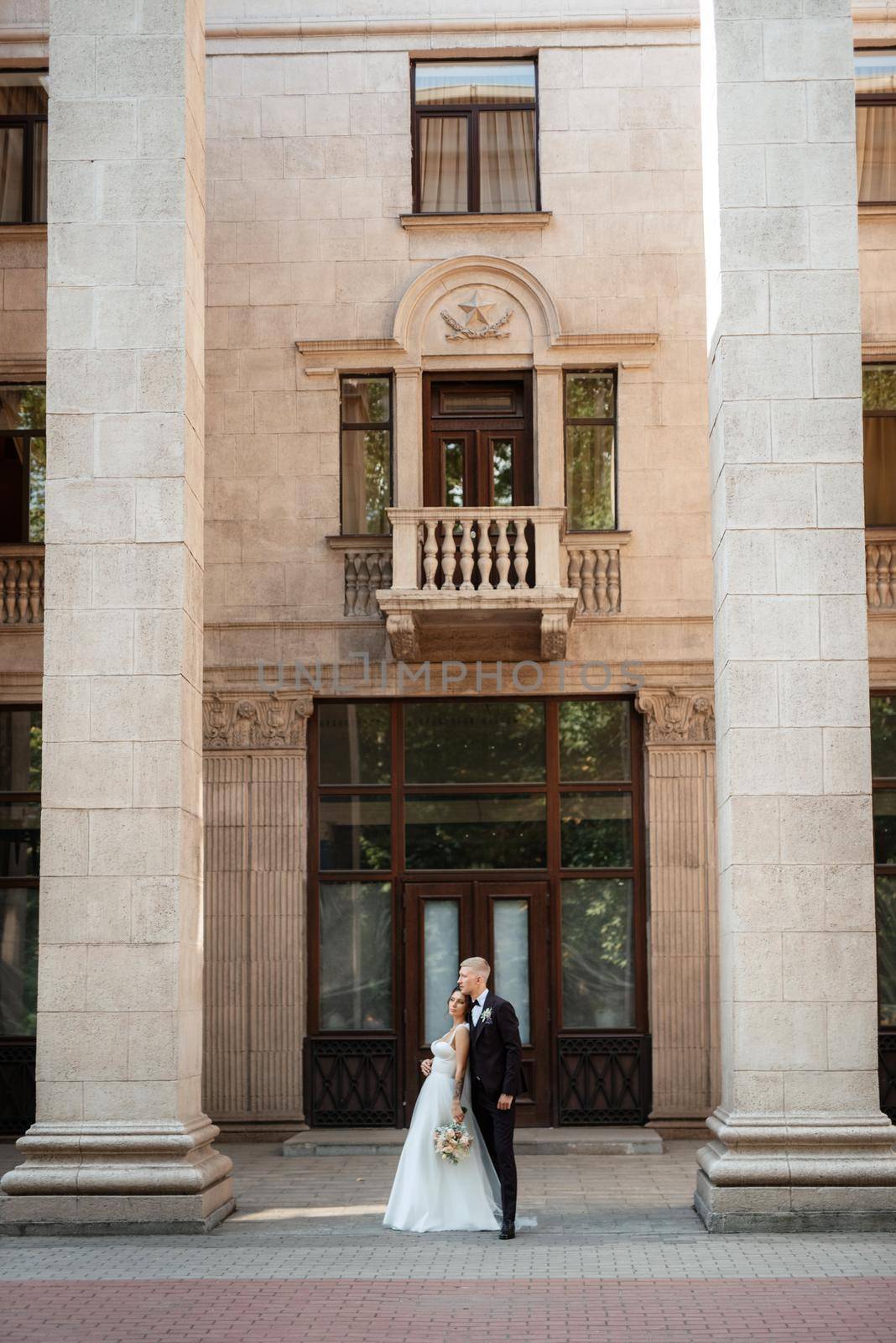 the groom in a brown suit and the bride in a white dress in an urban atmosphere