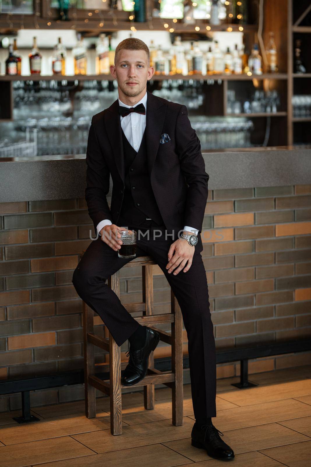 portrait of the groom in a brown three-piece suit with a bow tie on the wedding day