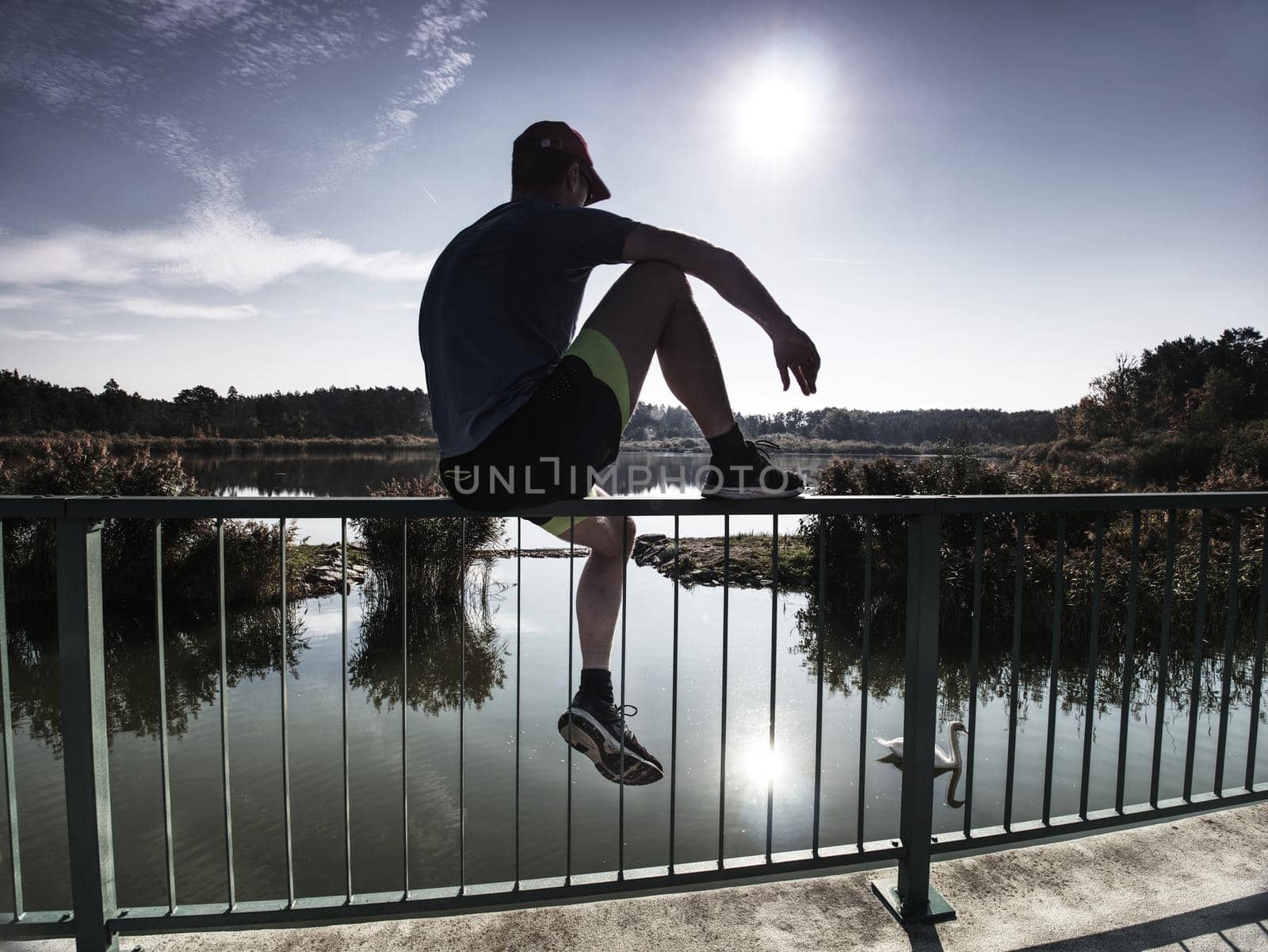 Sportsman is sitting on handrail in the park. Feet of jogging man by rdonar2