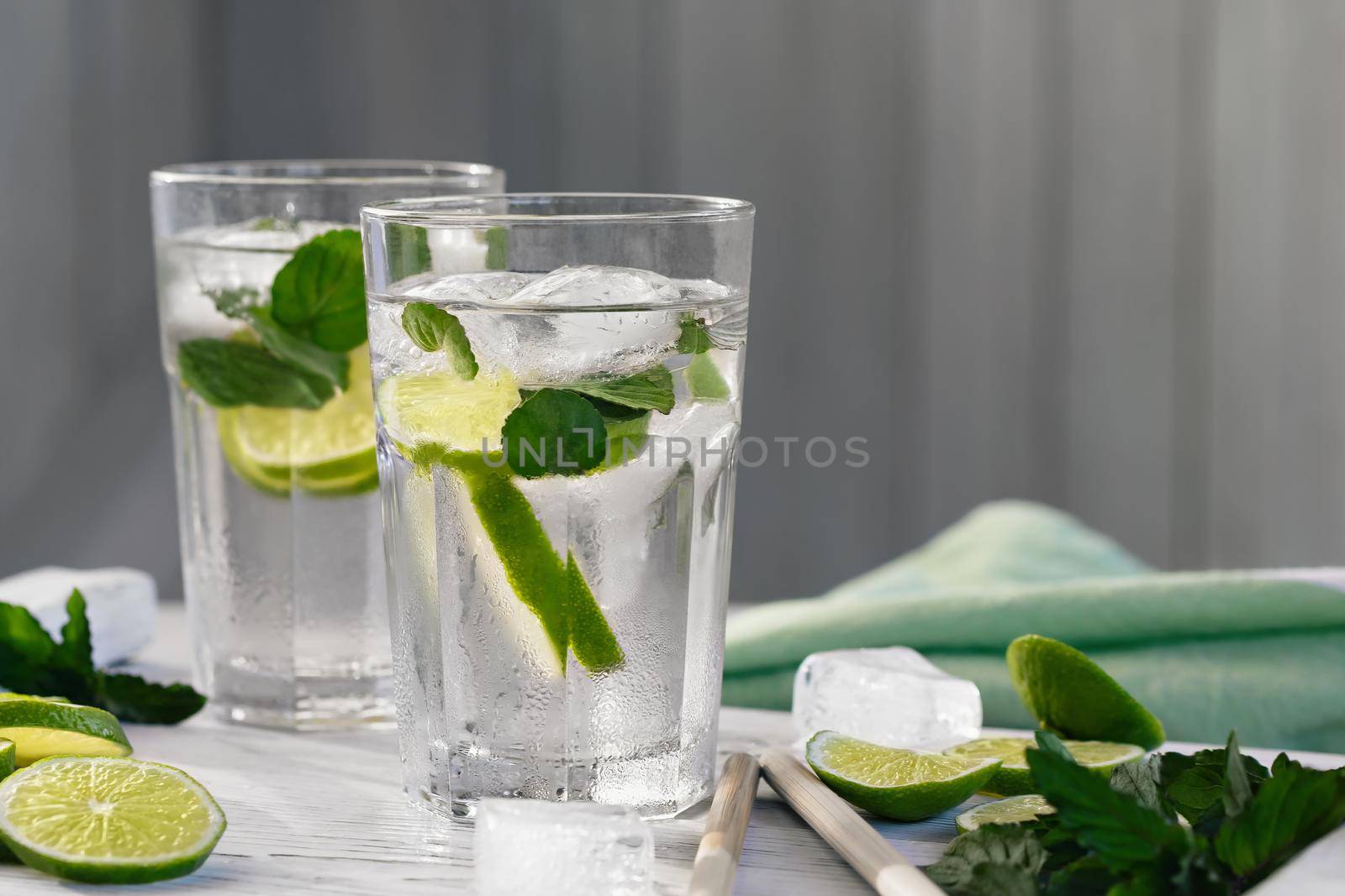 Summer refreshing mojito cocktails with lime and mint on a white wooden tray.