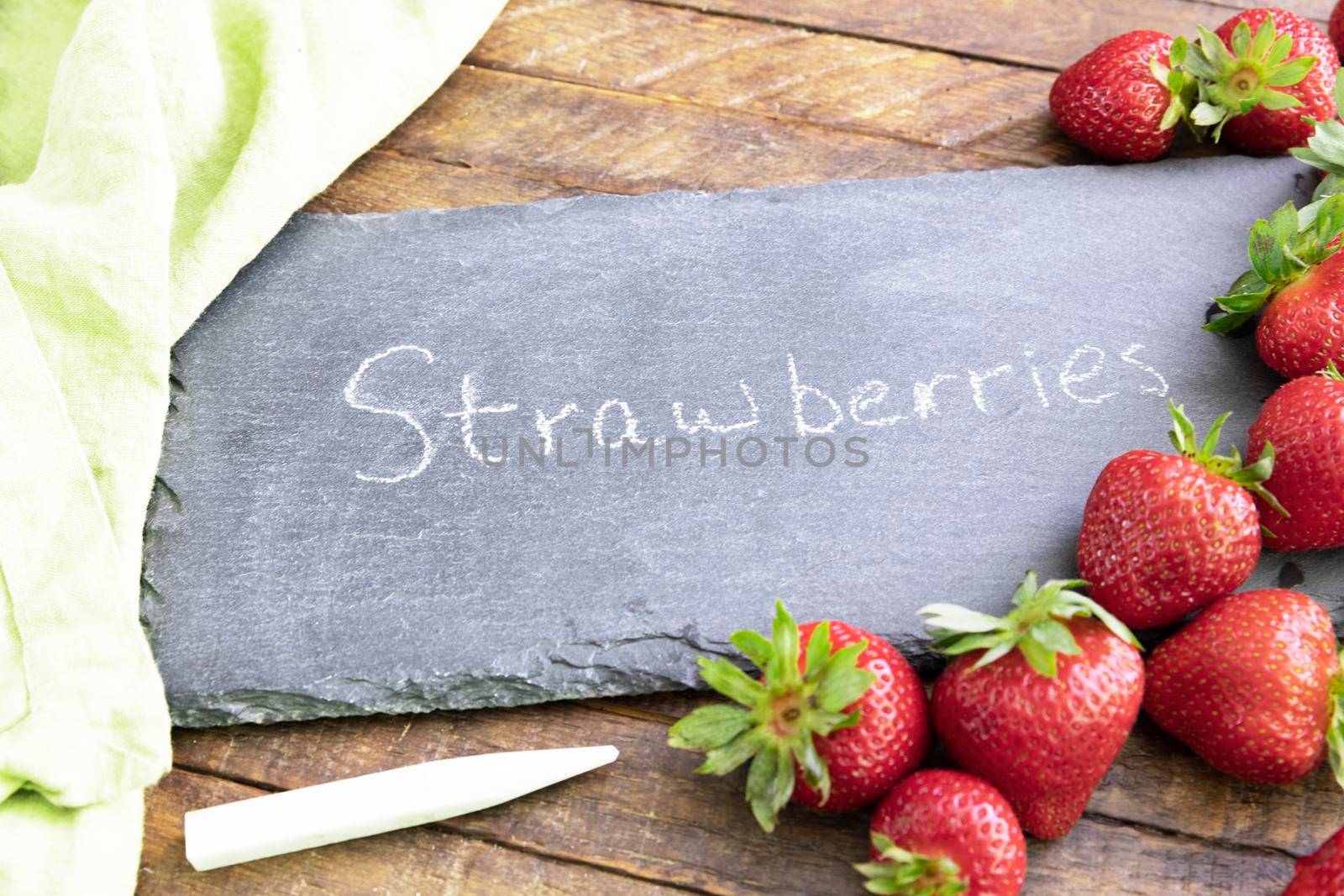 Fresh strawberries and a chalkboard sign with strowberries written on it