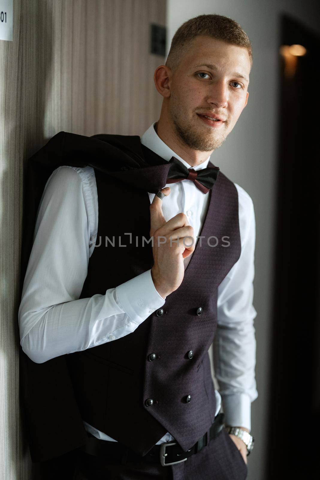 portrait of the groom in a brown three-piece suit with a bow tie on the wedding day