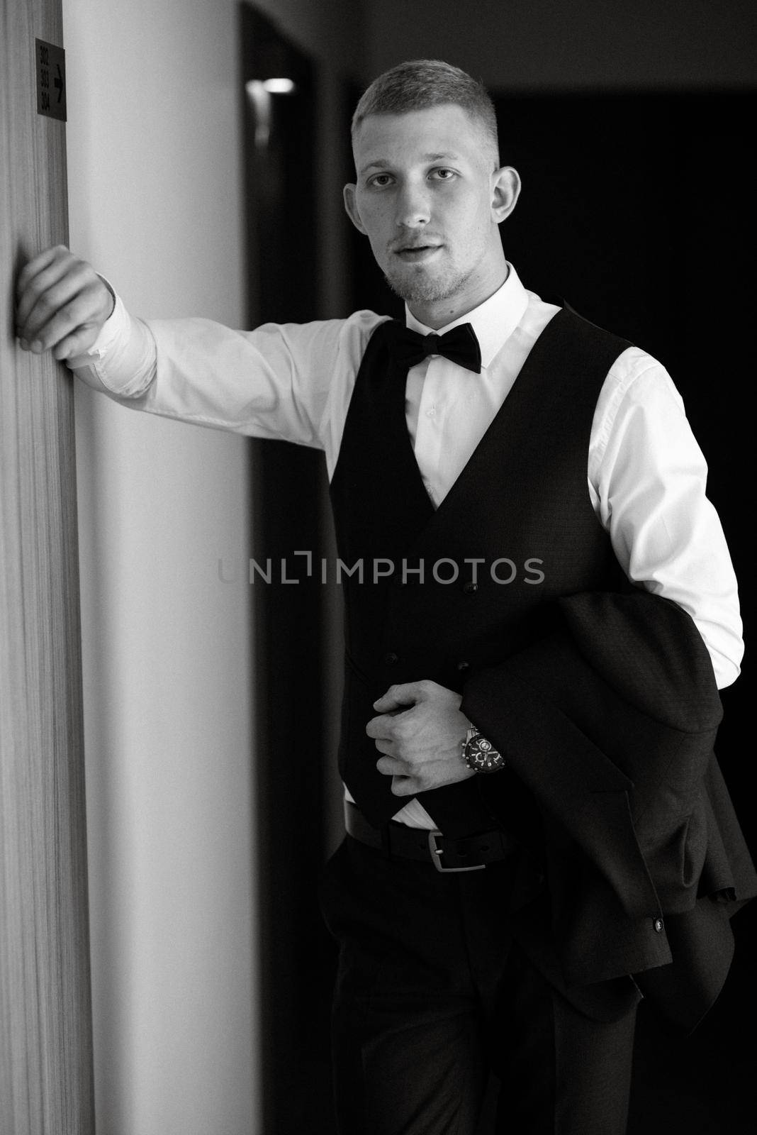 portrait of the groom in a brown three-piece suit with a bow tie on the wedding day