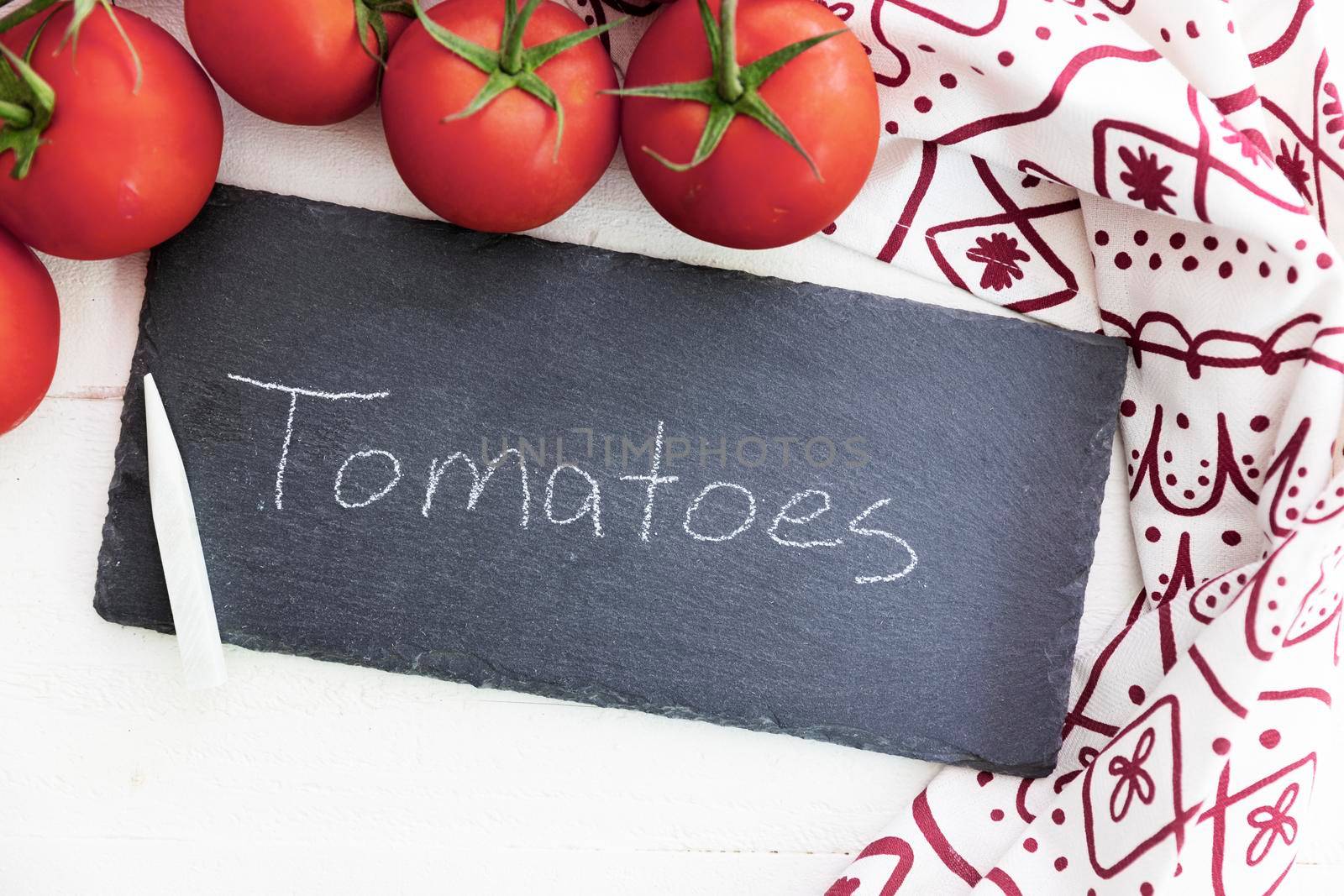 Fresh tomatoes and a chalkboard sign with tomatoes written on it.