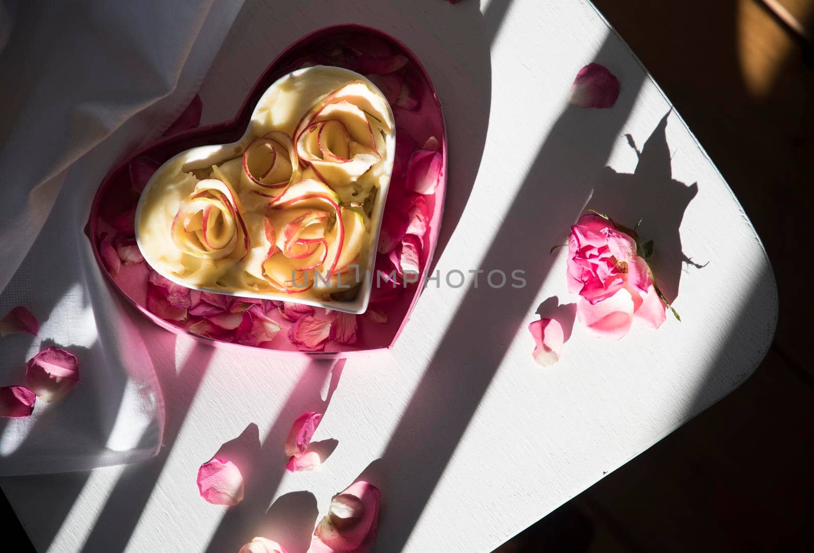 apple pie in the shape of a heart stands on a white chair in the rays of the sun shadow and light contrasting pattern homemade cakes for Valentine's Day, Mother's Day. High quality photo