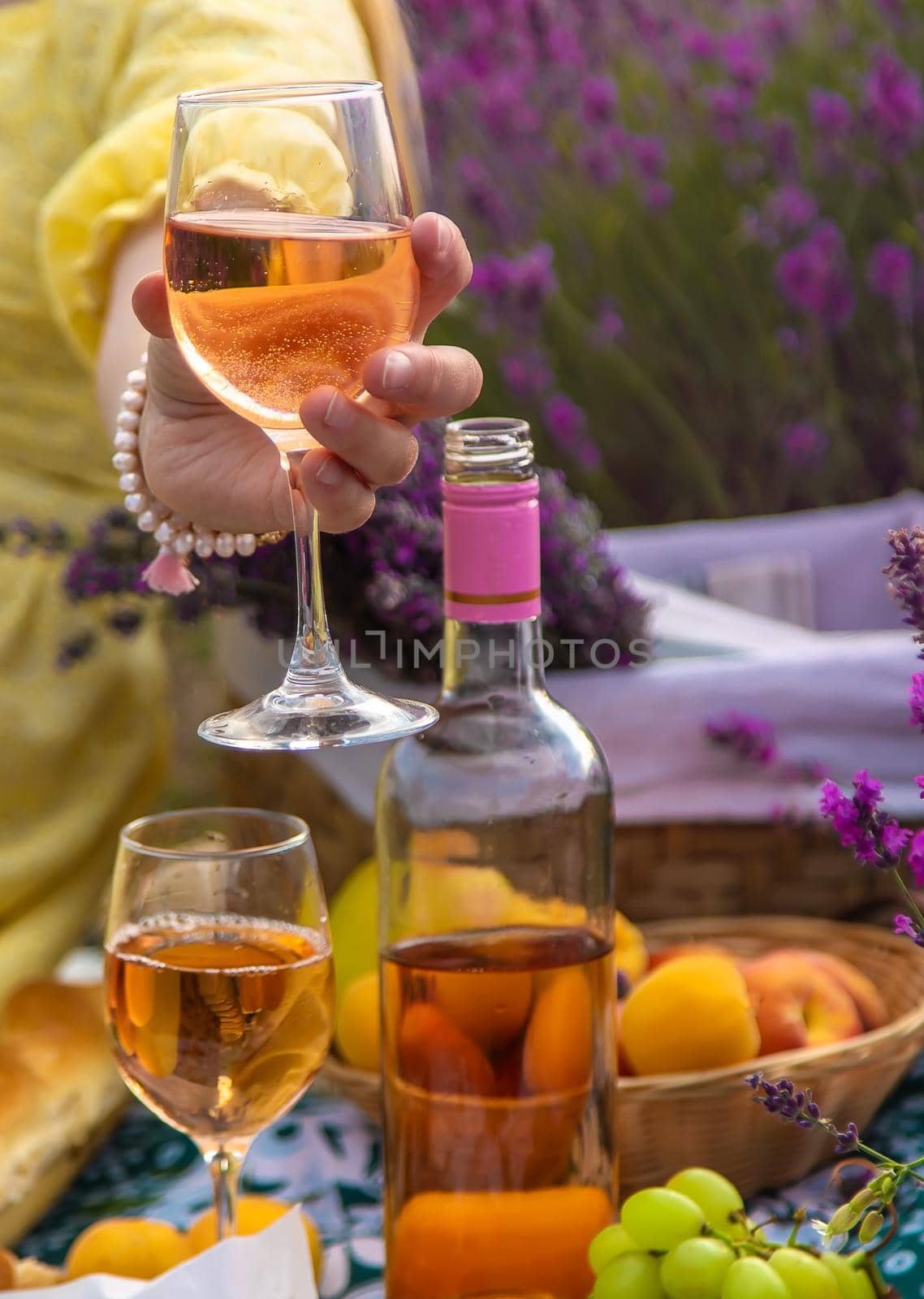 A woman drinks wine in a lavender field. Selective focus. by yanadjana
