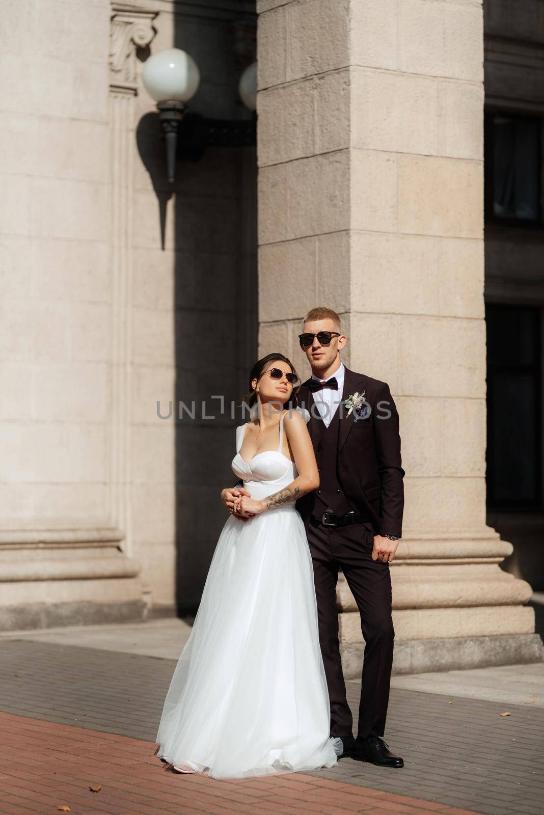 the groom in a brown suit and the bride in a white dress in an urban atmosphere