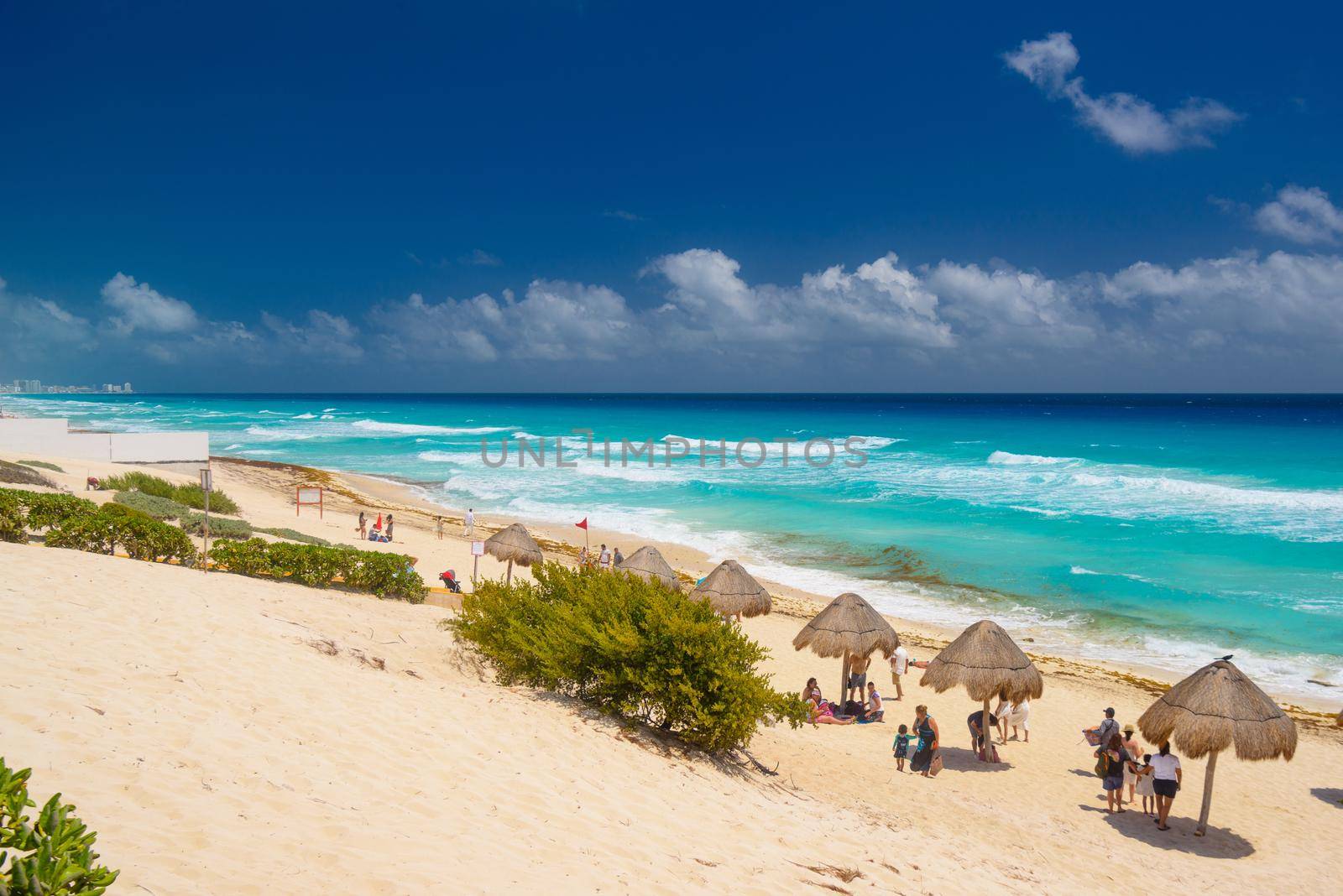 Umbrelas on a sandy beach with azure water on a sunny day near Cancun, Mexico.