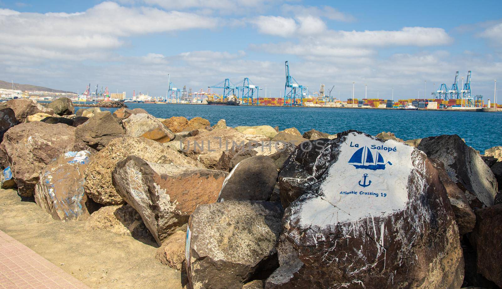 Paintings on stones in the harbour of Las Palmas de Gran Canary Spain, in the background you can see the industrial harbour