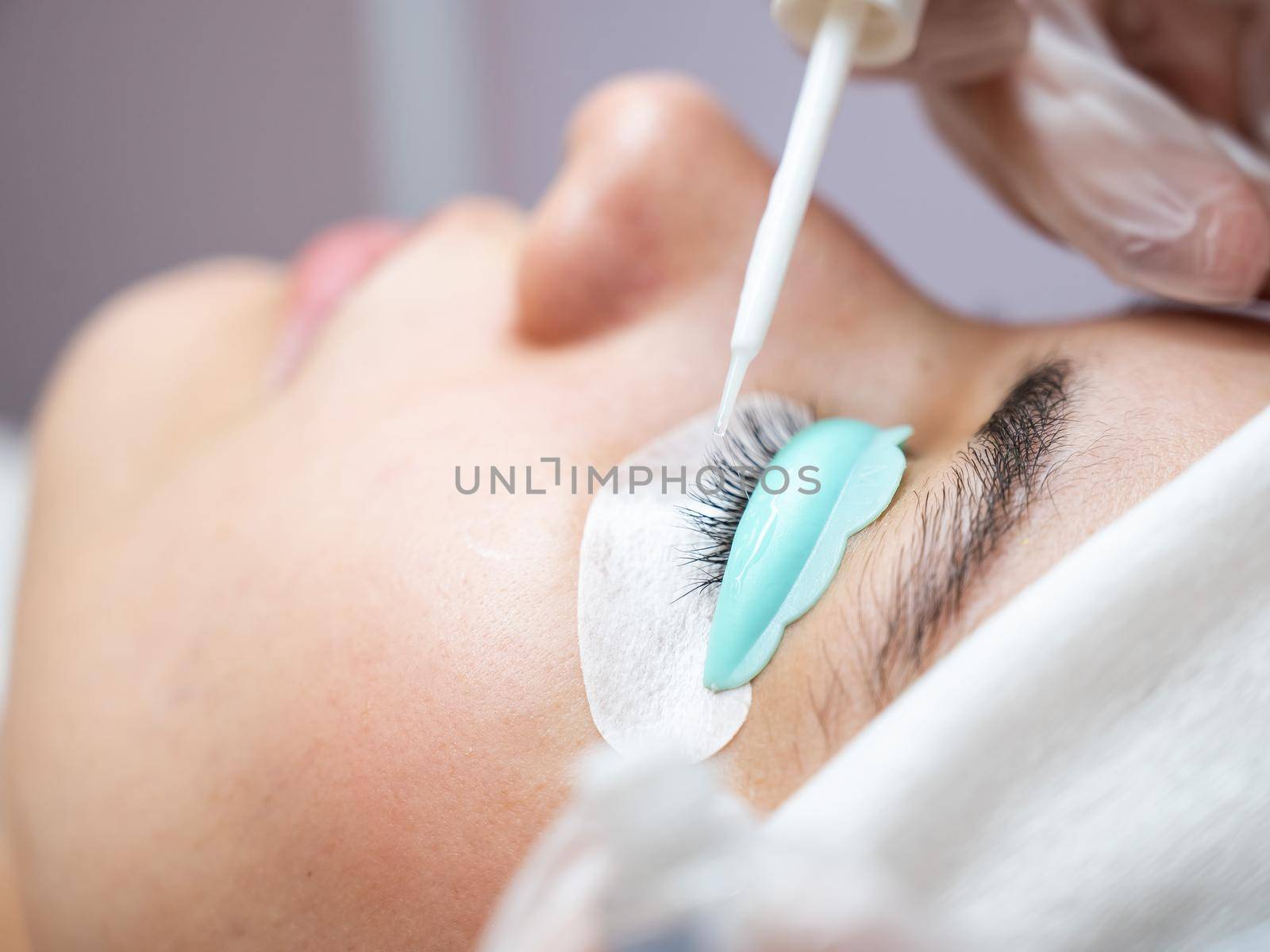 Young woman undergoing eyelash tinting and lamination procedure. by mrwed54