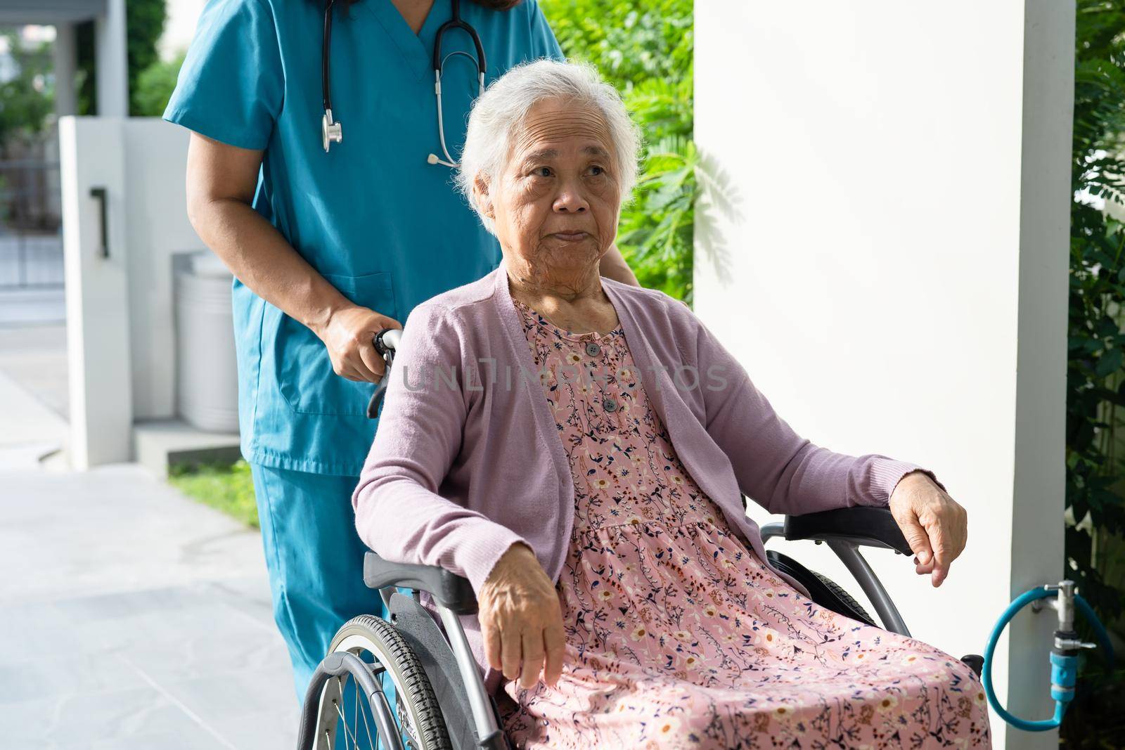 Doctor caregiver help and care Asian senior or elderly old lady woman patient sitting on wheelchair in park at nursing hospital, healthy strong medical concept by pamai