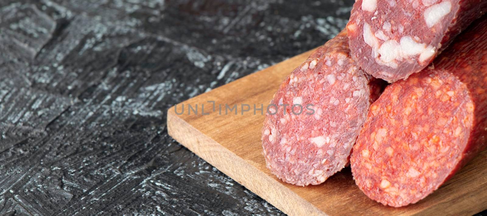 banner with close-up three kinds of different sausages on a cutting board on a black textured background. by Leoschka