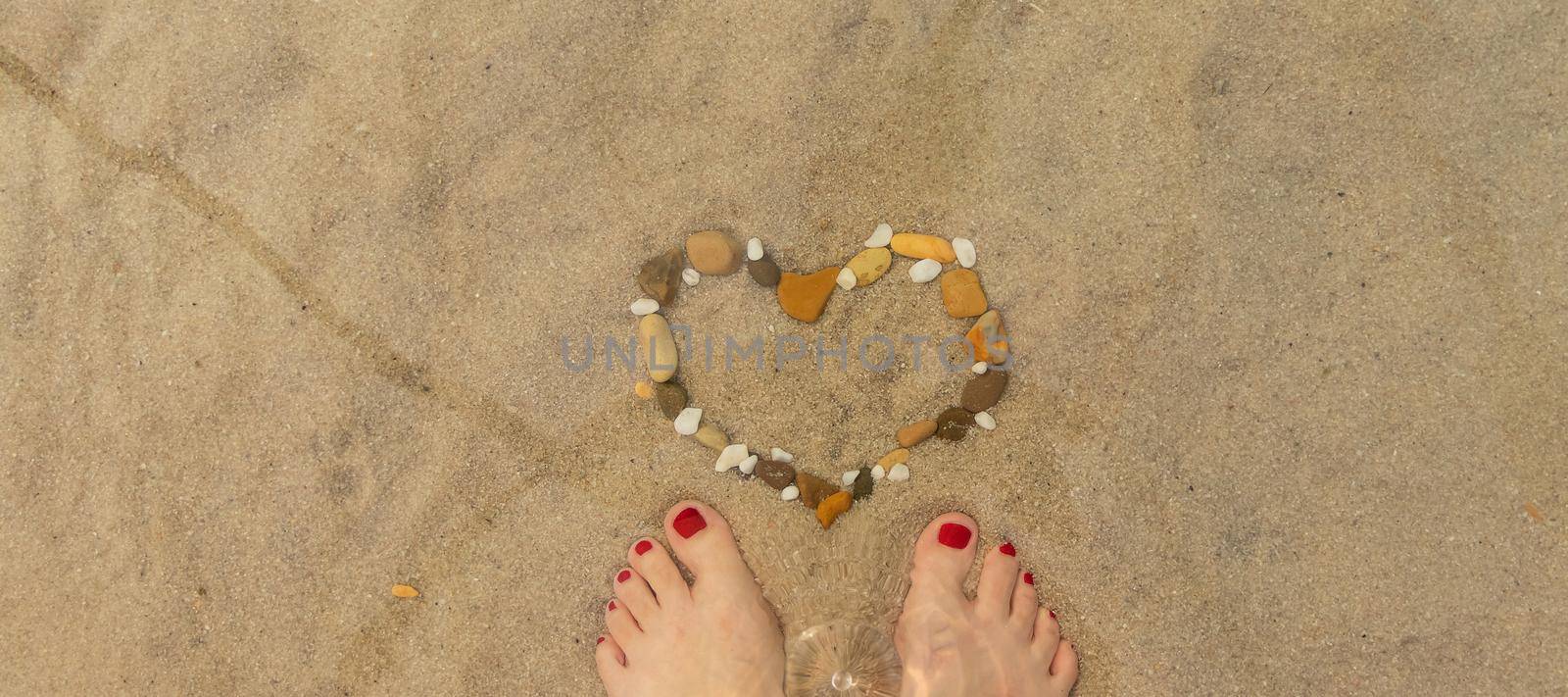 banner with women's feet onbeach and heart is laid out of pebbles. relaxing on beach, summer by sea by Leoschka