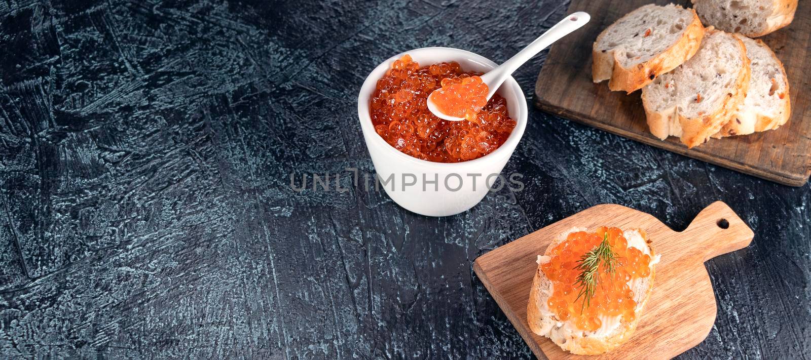 banner with baguette, red caviar, dill on black background with copy space. Cooking process. Recipe for making an appetizer with red caviar. Top view.