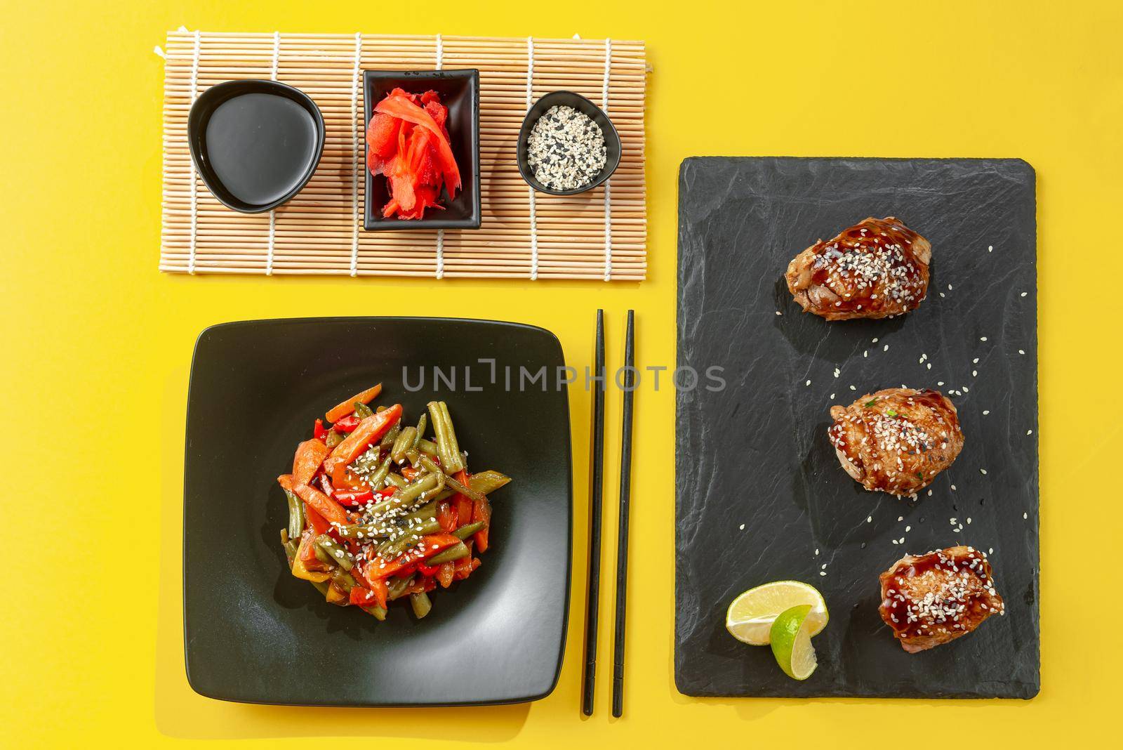 A mix of Asian food on a gray background. Delicious Chinese and Thai street food on a bright yellow background. Chinese fried vegetables with other Asian food on a dark background. Teriyaki chicken and roasted Korean vegetables. Asian food mix. Top view and flat lay