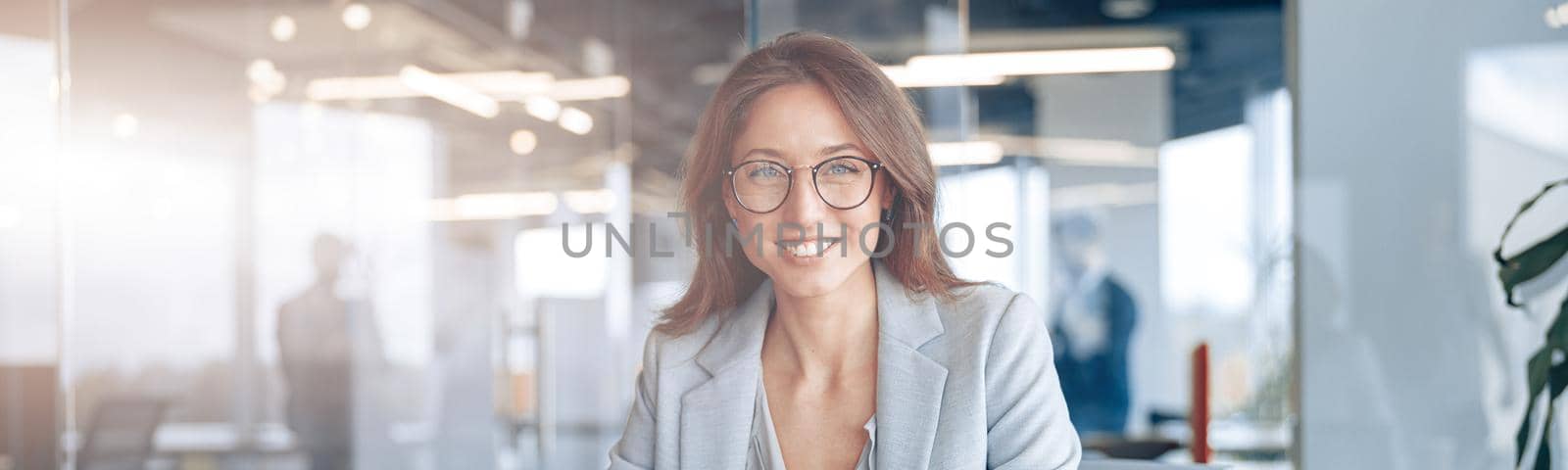 Portrait of smiling businesswoman working on laptop at her workplace at modern office.