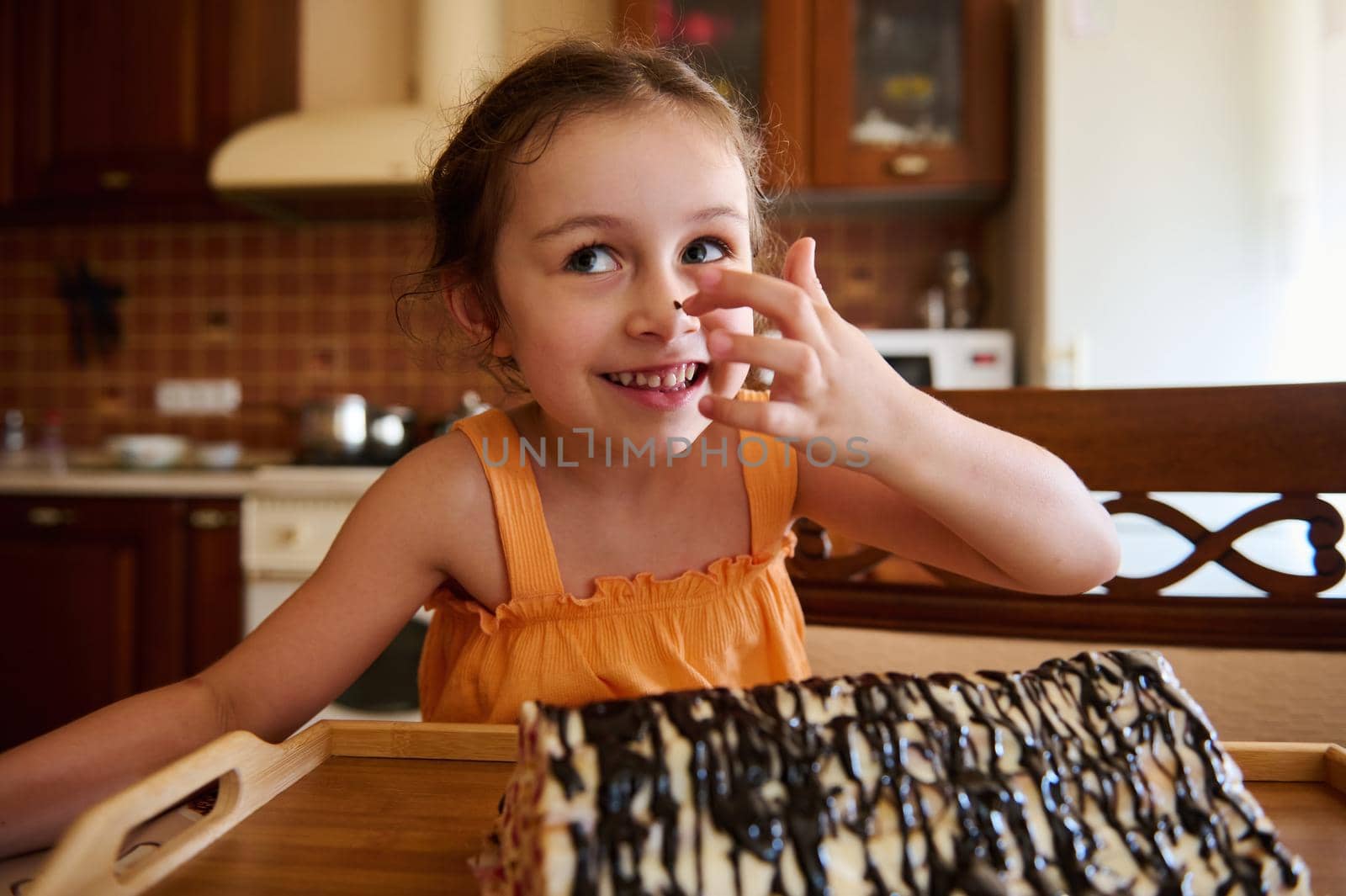 Beautiful and cheerful child, European baby girl standing at kitchen island and looking at summer sweet homemade cherry dessert- Monastery hut