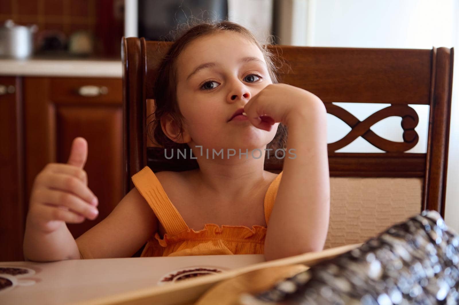 Adorable child, European baby girl sitting a dining table with served homemade cake, cherry pie, sweet dessert- Monastery hut in the home kitchen interior