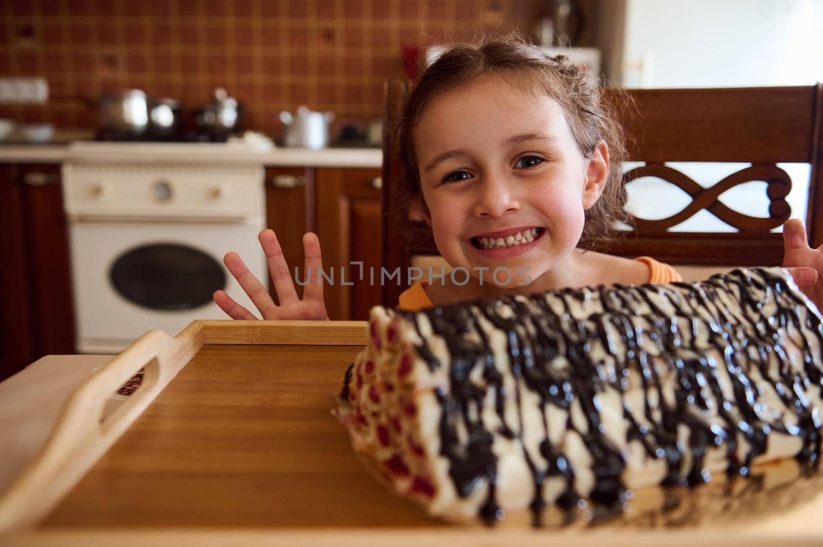 Beautiful and cheerful child, Caucasian baby girl standing at kitchen island and looking at summer sweet homemade cherry dessert- Monastery hut