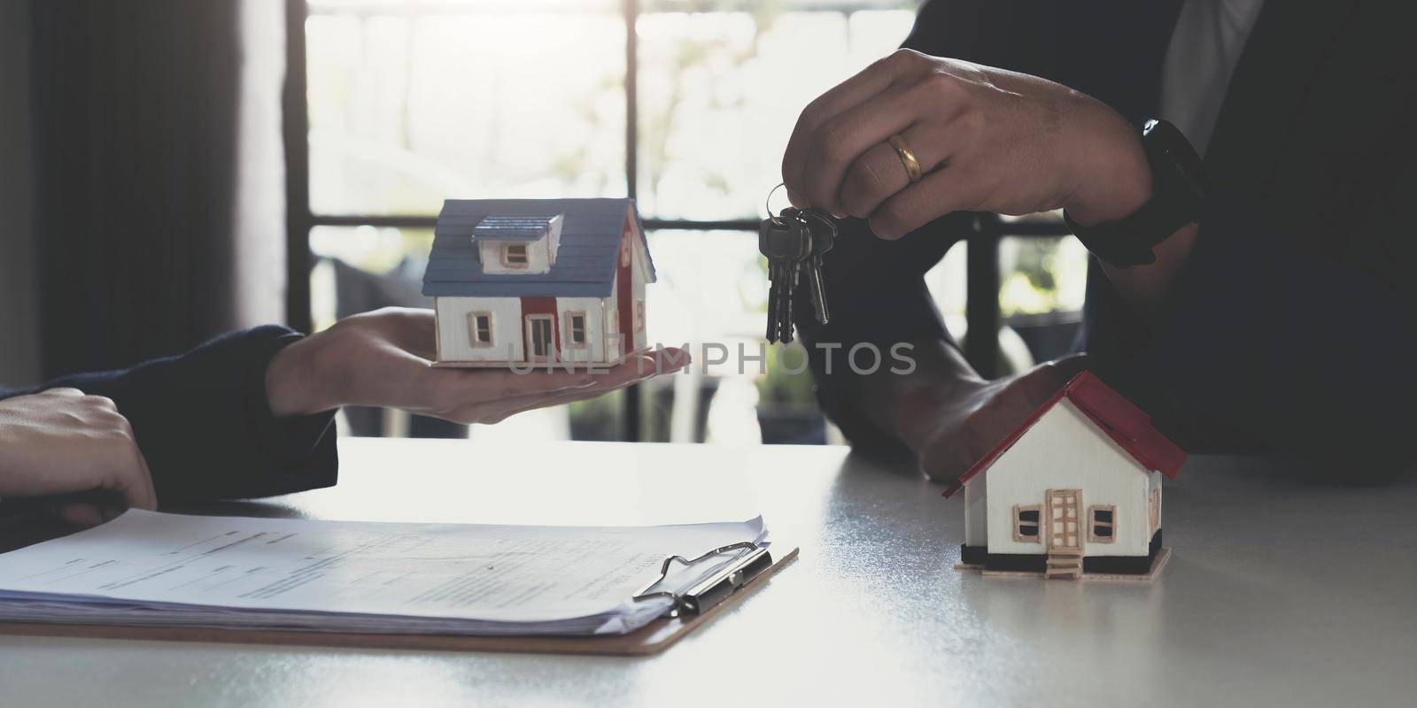 Buying real estate and agreement concept. Real estate agents agree to buy a home and give keys to clients at their agency's offices..