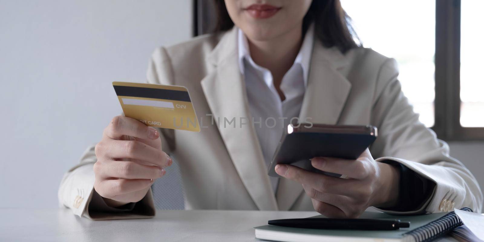 Close up hand of business woman using a credit card and mobile smartphone for payments and online shopping, Online shopping, digital banking, E-commerce concept..