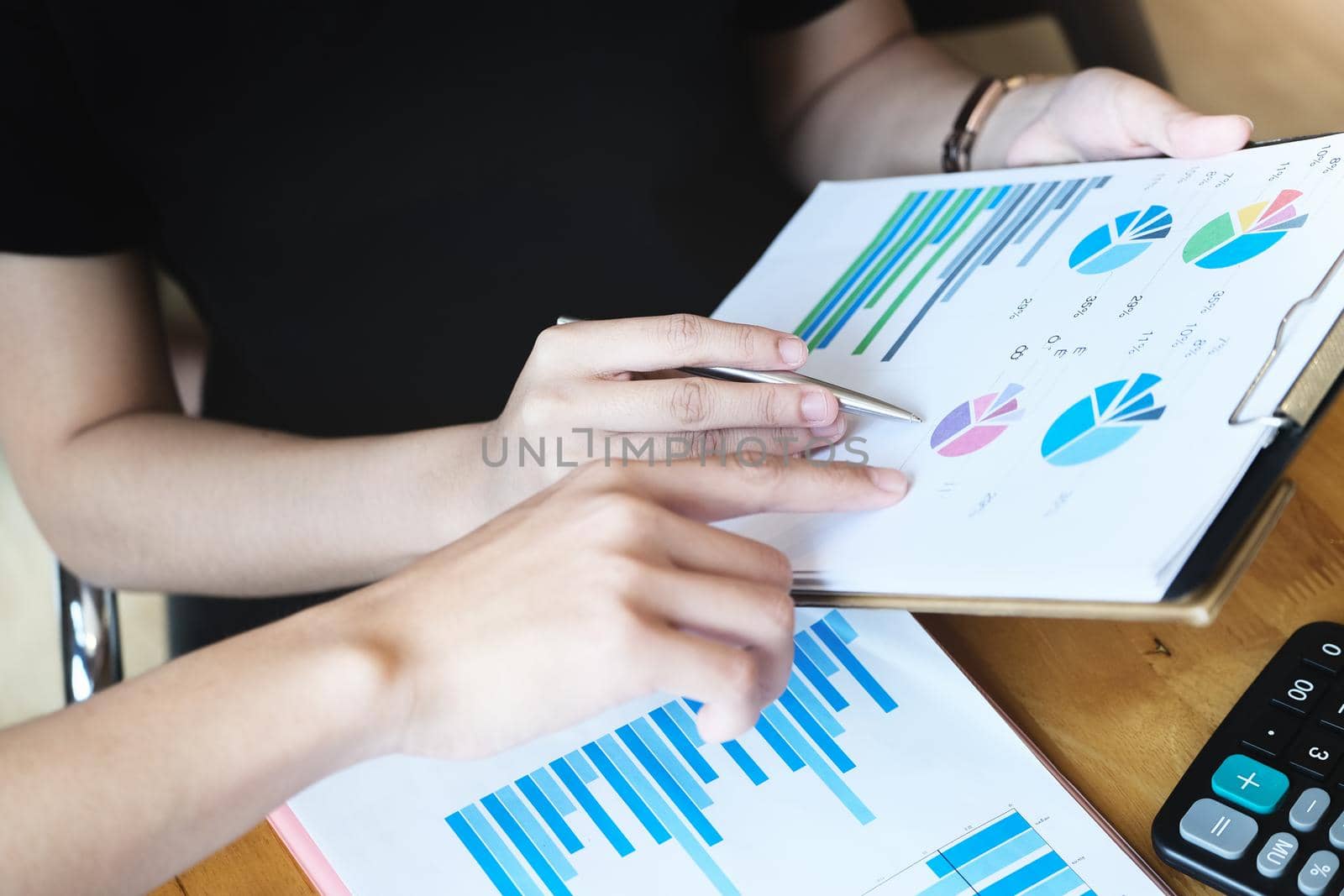 focus hand holding pen point to chart document with business woman and partnership discussion and exchange of ideas during work by Manastrong