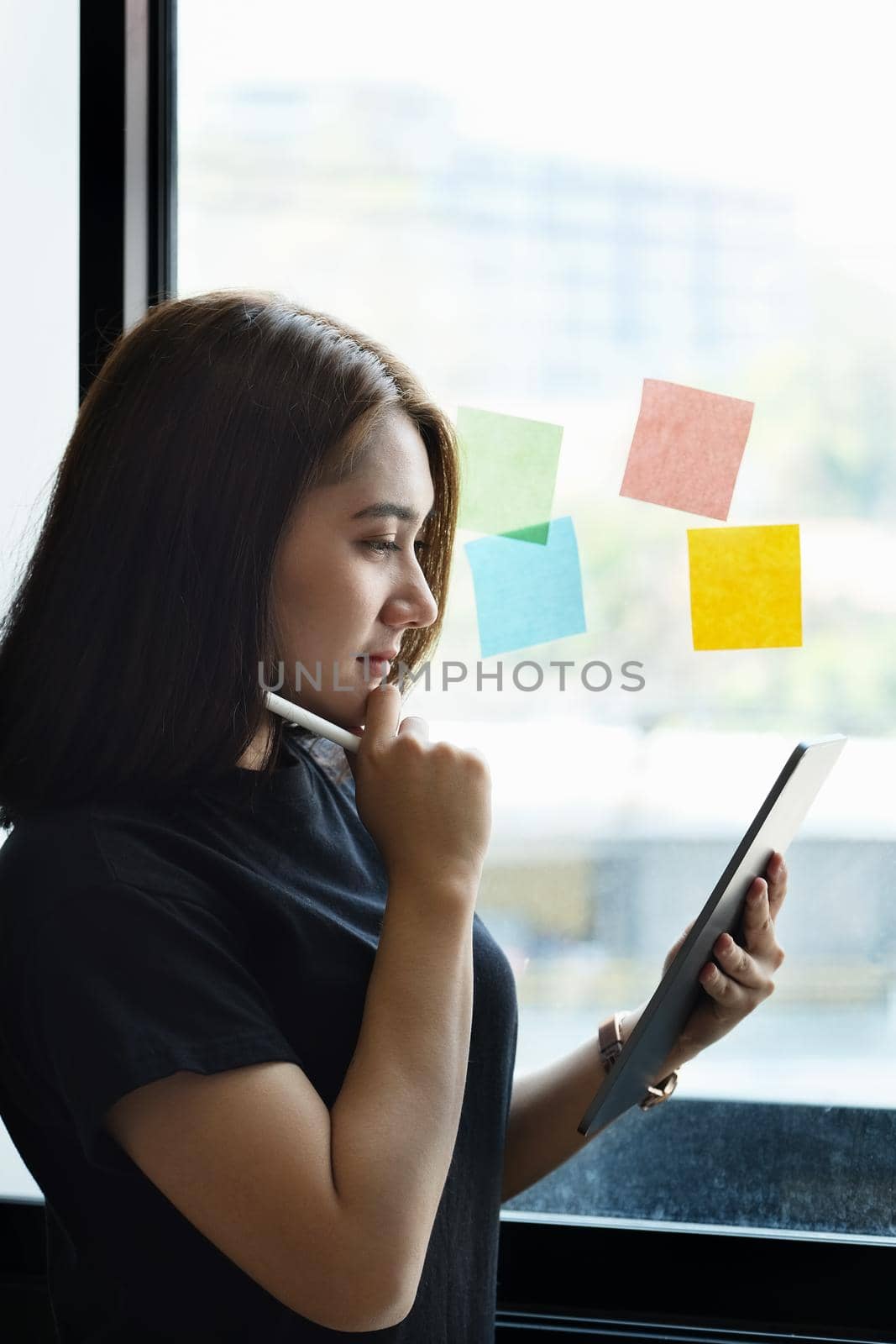 A female company employee uses a tablet and notepad to analyze company budgets