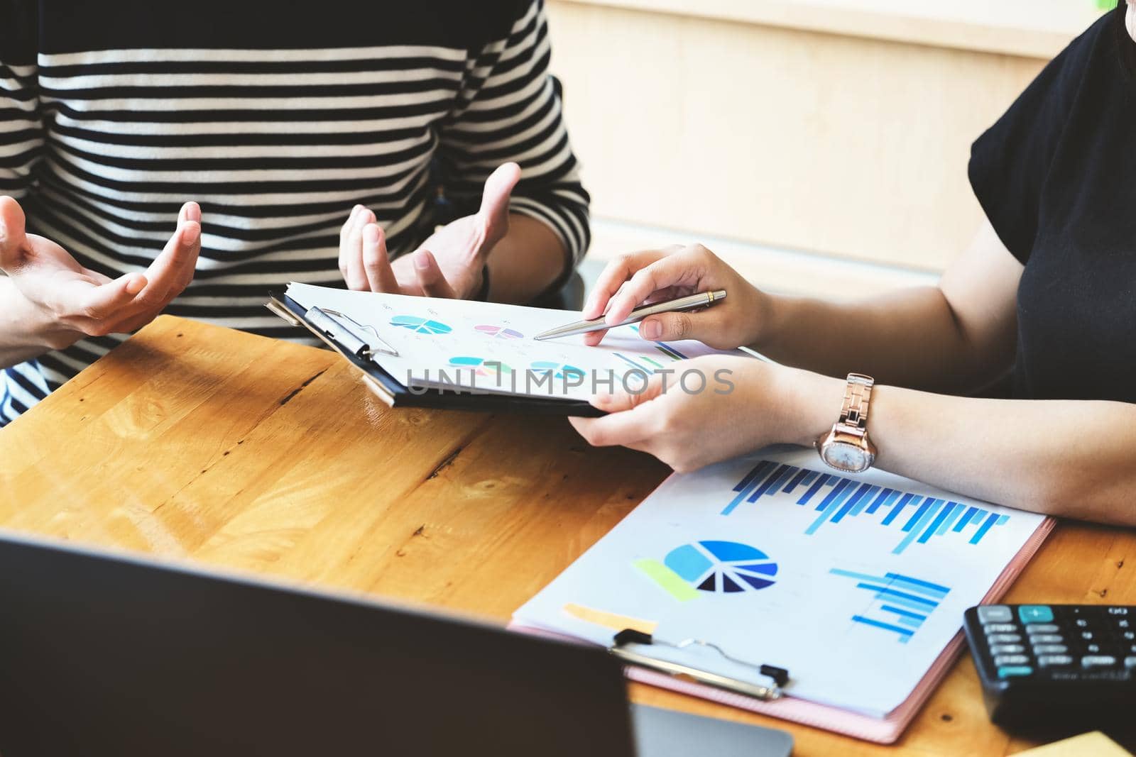 focus hand holding pen point to chart document with business woman and partnership discussion and exchange of ideas during work by Manastrong