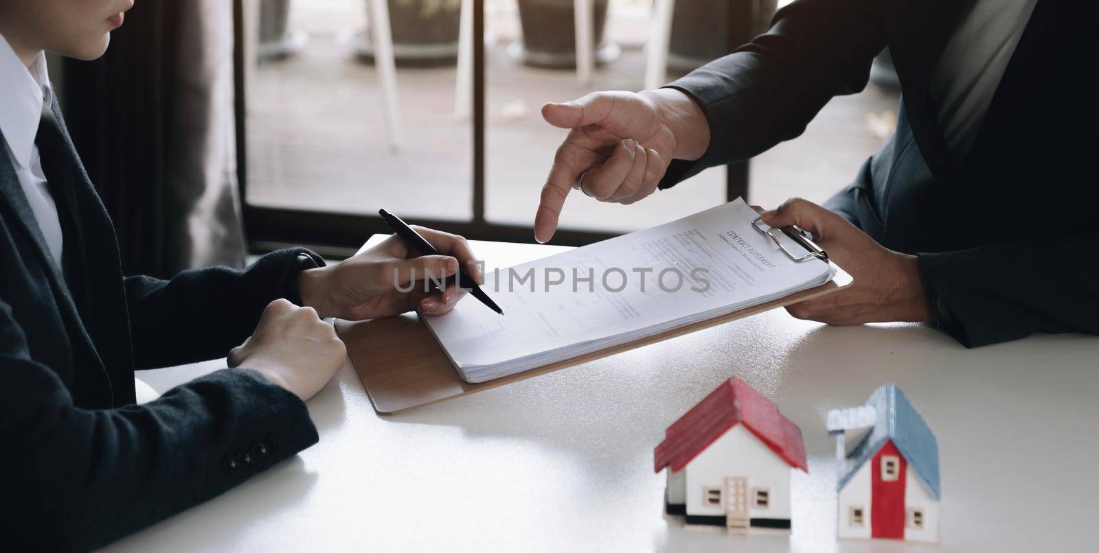 A real estate agent with a House model is talking to clients about buying home insurance. Home insurance concept..