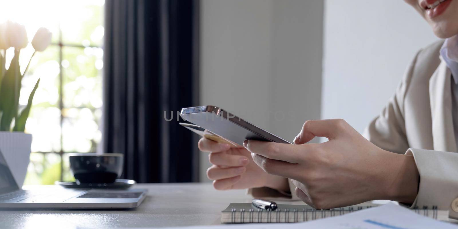 Close up hand of business woman using a credit card and mobile smartphone for payments and online shopping, Online shopping, digital banking, E-commerce concept. by wichayada