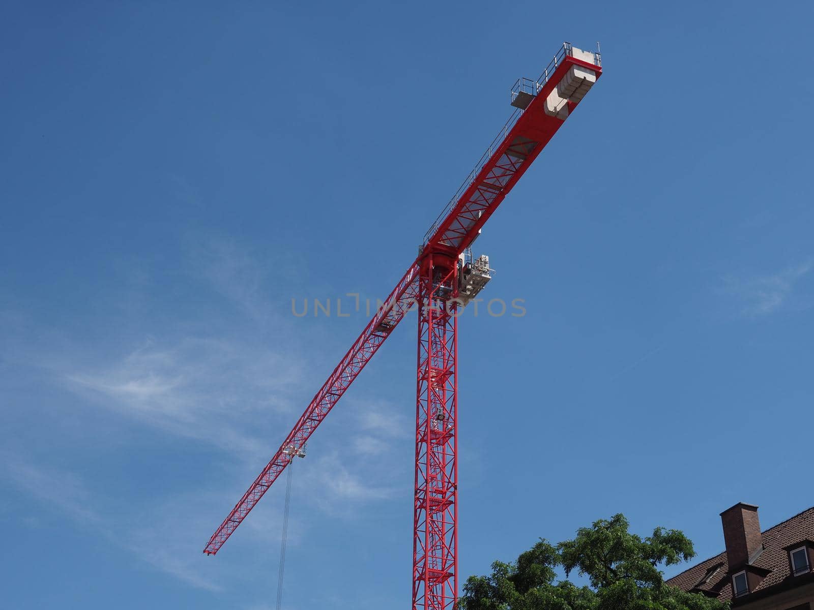red building crane in a construction site over blue sky