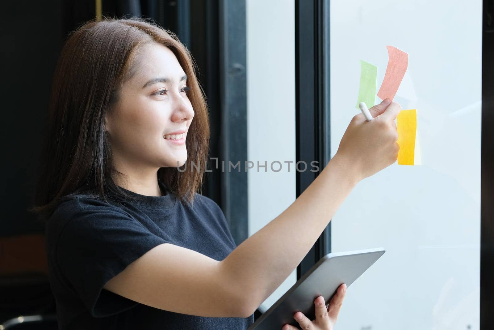 A female company employee using notepad and tablet to analyze company budgets. by Manastrong