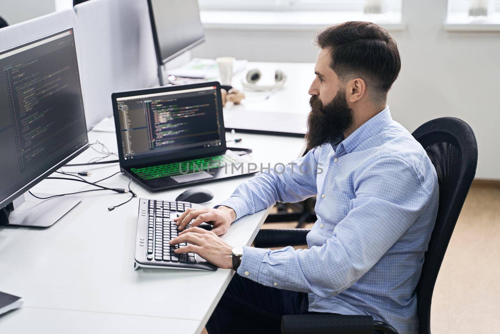 Senior developer working on computer in IT office, sitting at desk and coding, working on a project in software development company or technology startup.