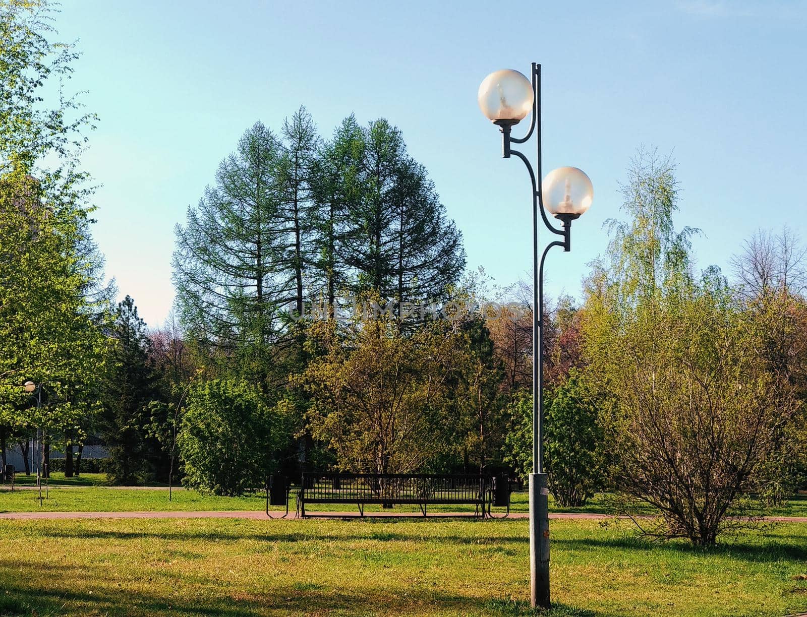 Lantern in the summer park on the background of trees and green grass by ProjectStockman