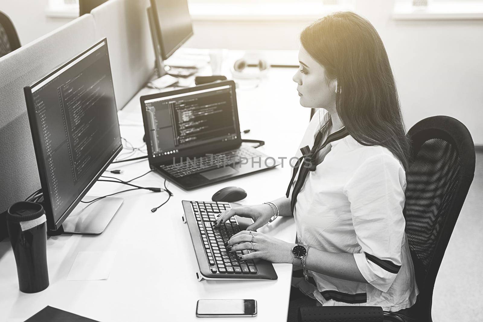 Beautiful young woman working on computer in IT office, sitting at desk and coding, working on a project in software development company or technology startup.