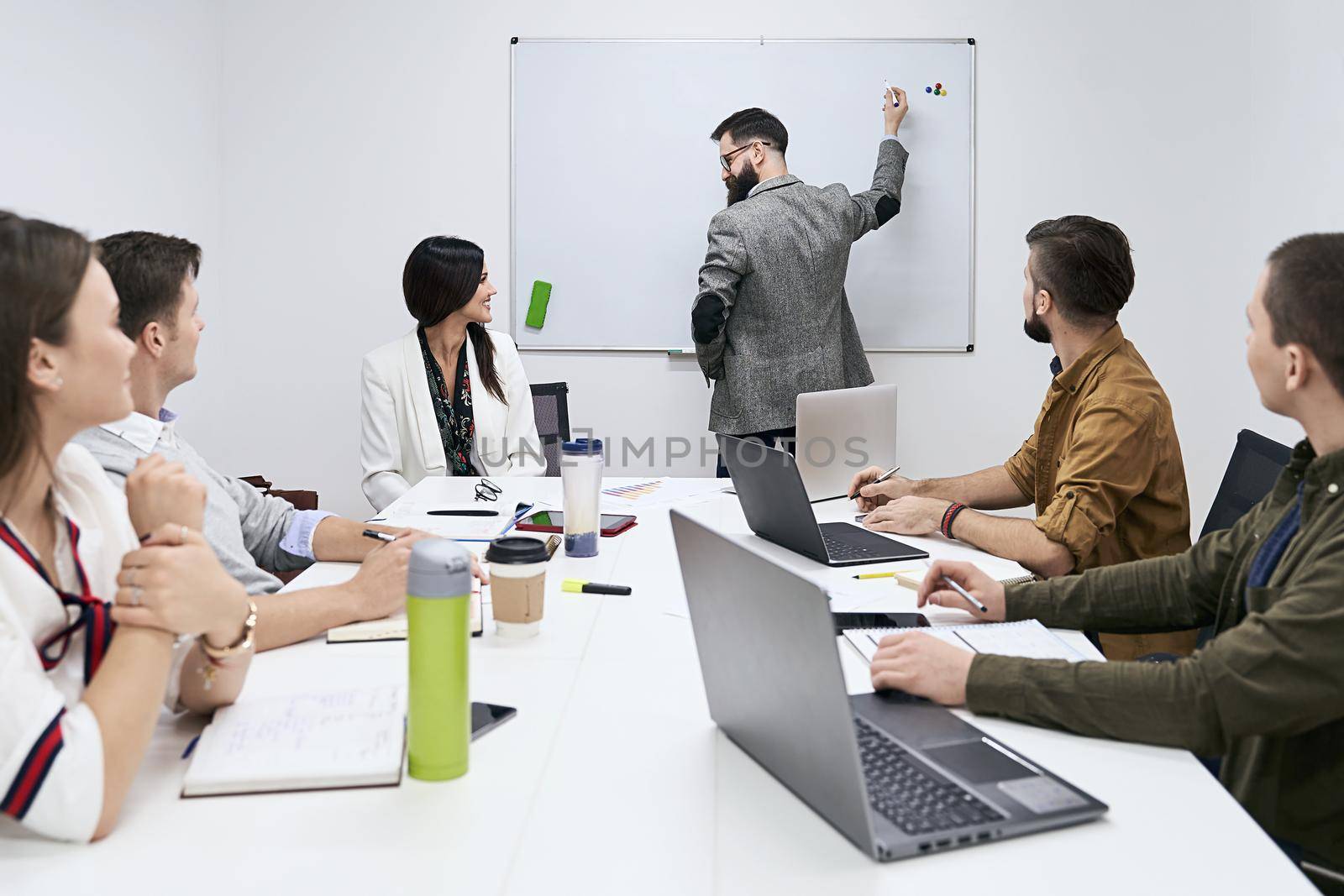 Male business coach speaker in suit give whiteboard presentation, speaker presenter consulting training persuading employees client group, mentor leader explain strategy at team meeting workshop by berezko