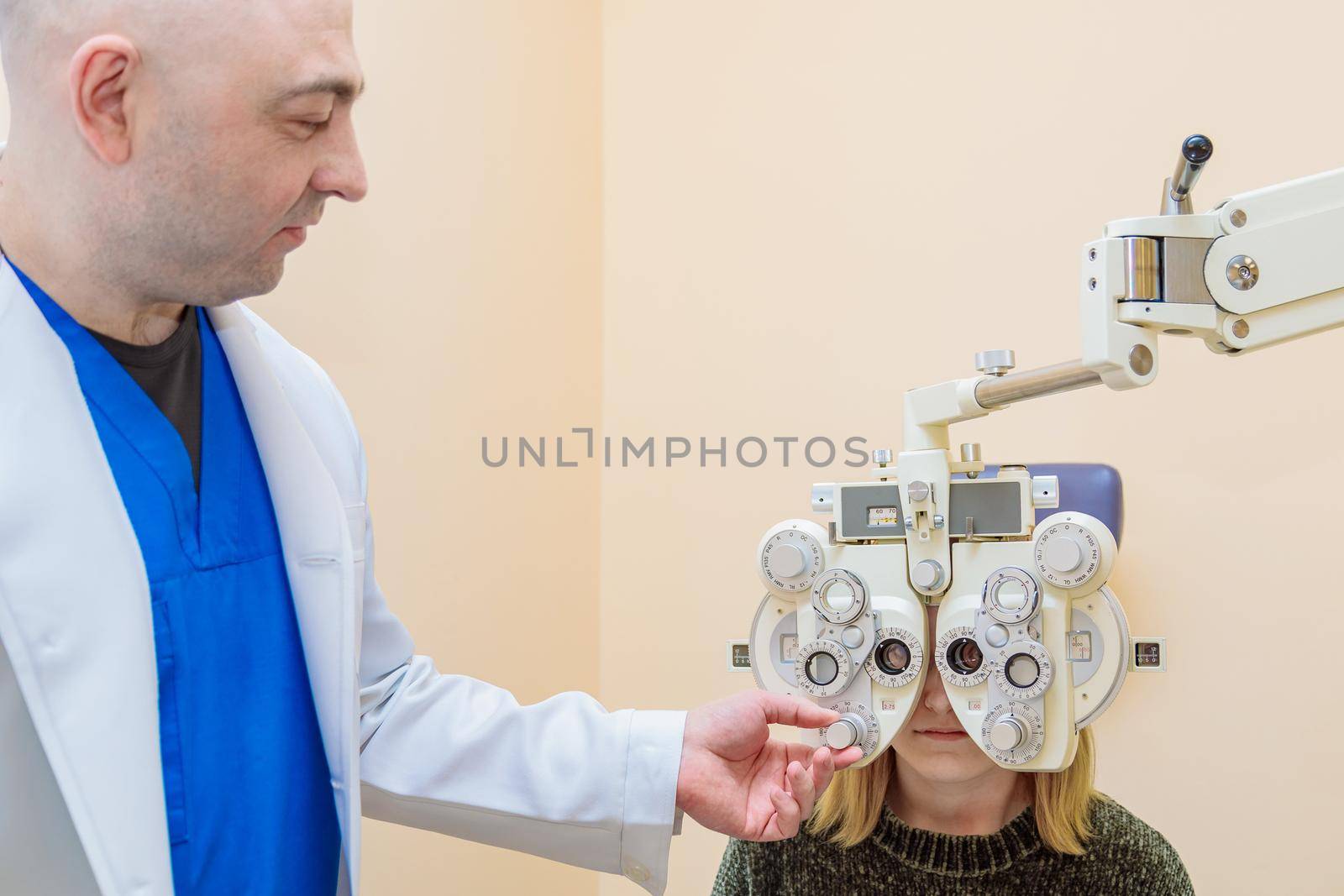 A male ophthalmologist checks a girl's eyesight using a phoropter. Vision treatment.