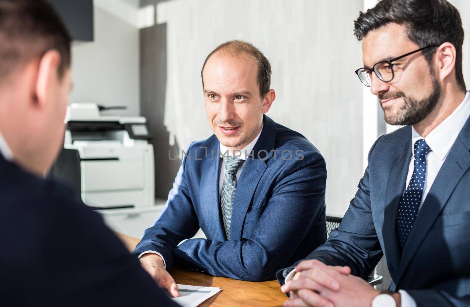 Team of confident successful business people discussing the contract terms at business meeting in modern corporate office. by kasto