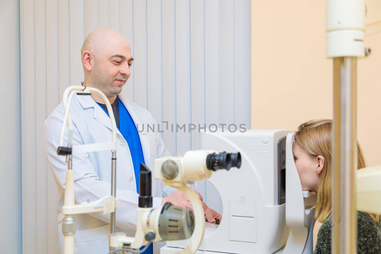 A male ophthalmologist checks the eyesight of a young girl using a modern vision tester.