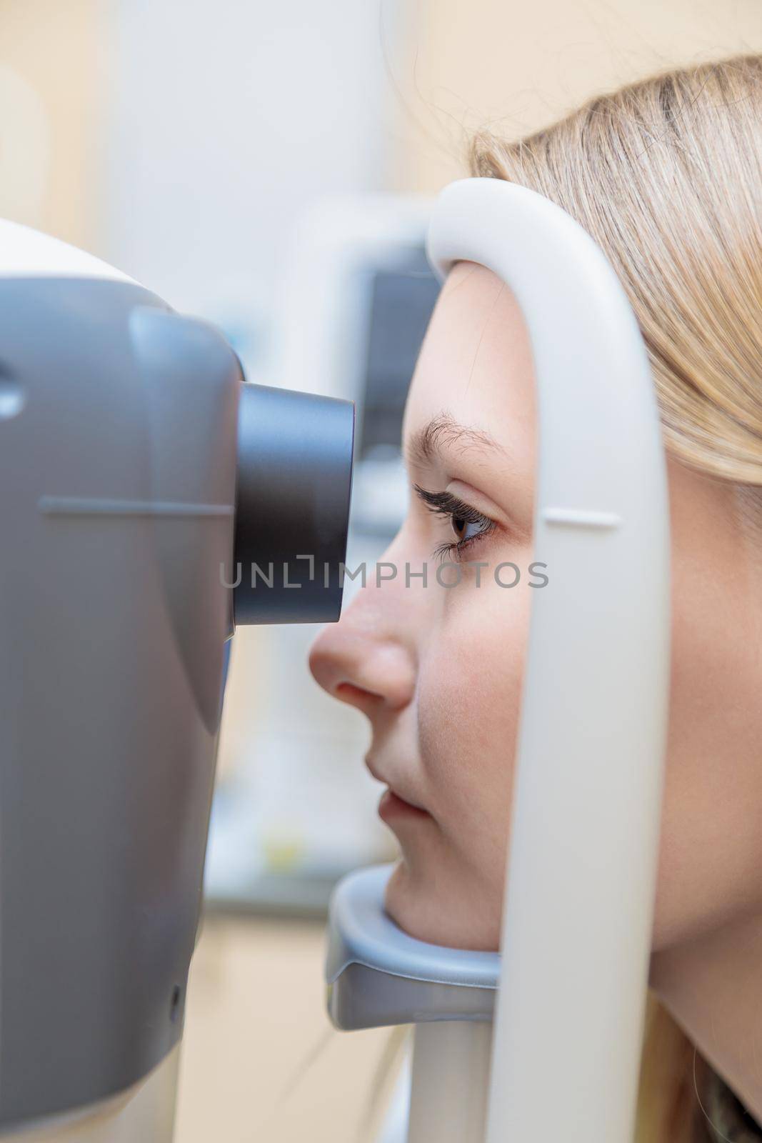 A young girl at the reception at the ophthalmologist checks her eyesight on a special apparatus. Close-up.
