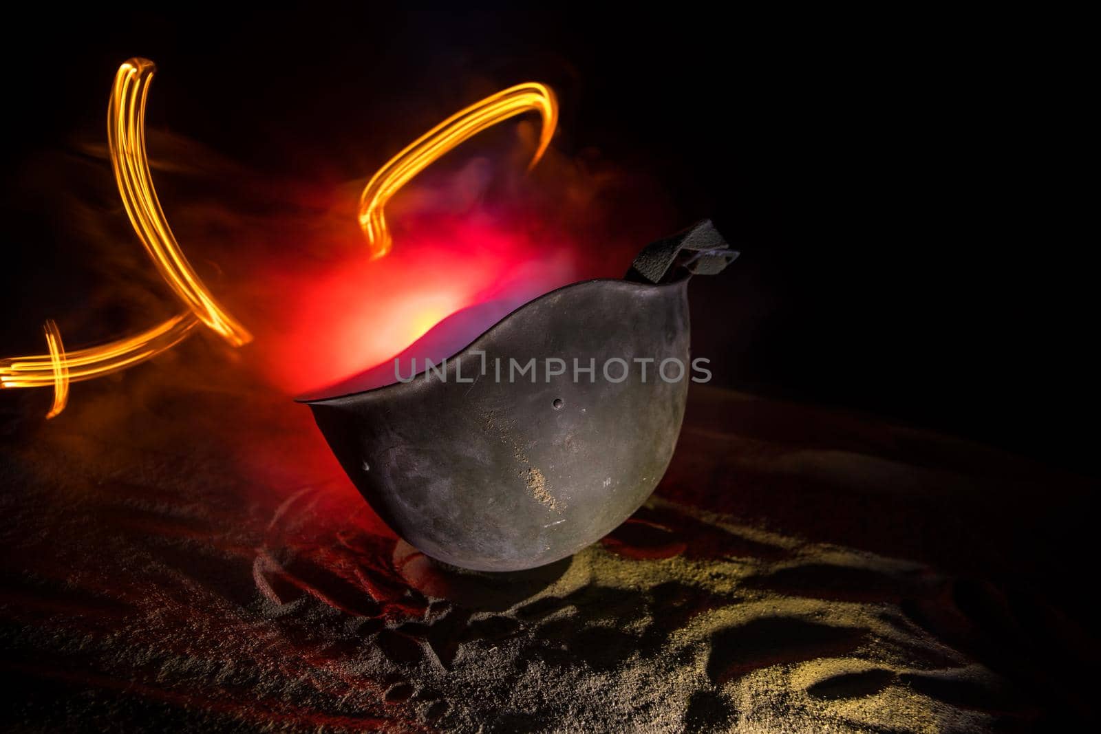 Soviet army Helmet Second World War on sand with backlight and smoke. War concept. Selective focus