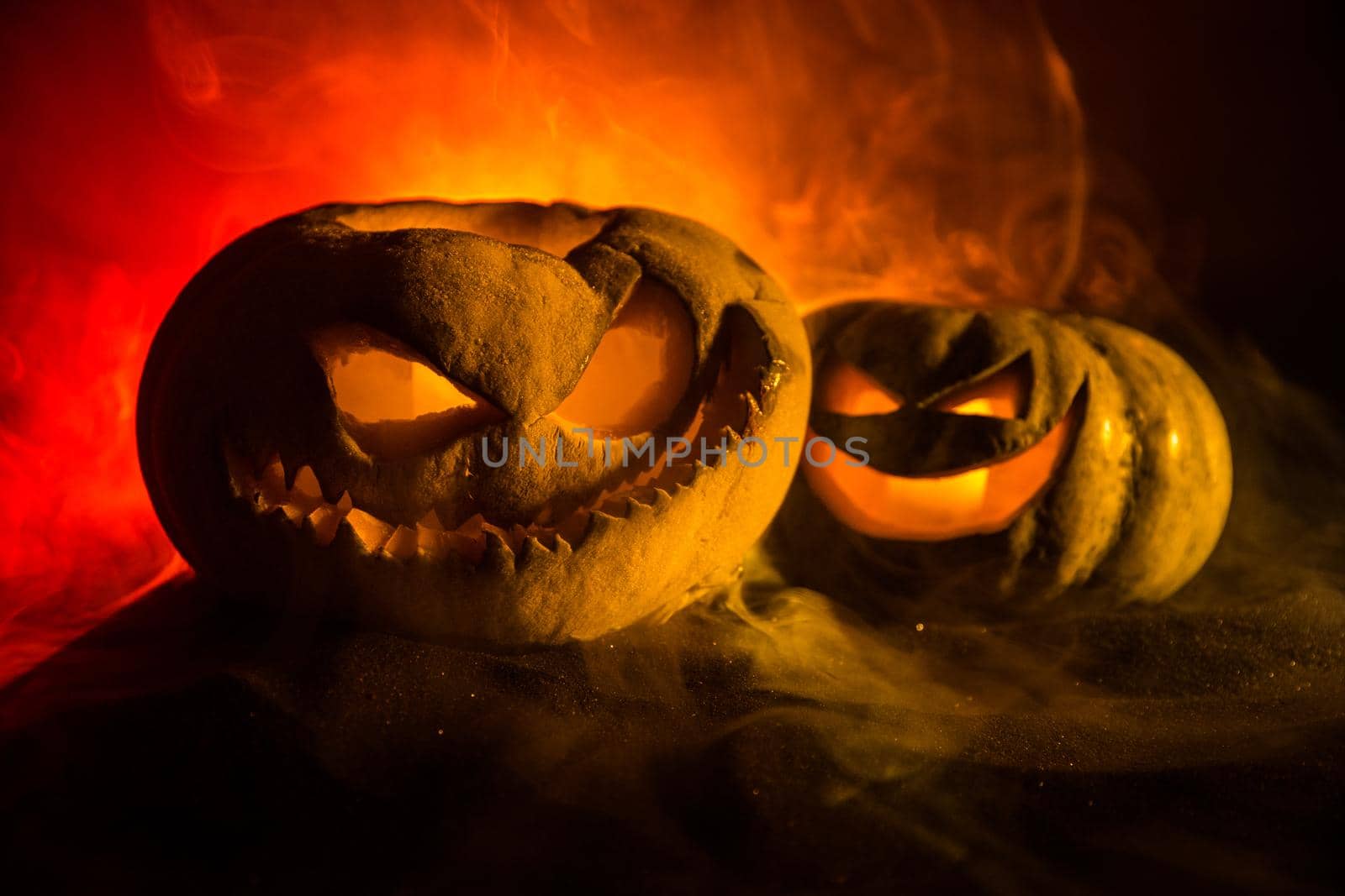 Halloween pumpkin smile and scary eyes for party night. Close up view of scary Halloween pumpkin with eyes glowing inside at black background. Selective focus