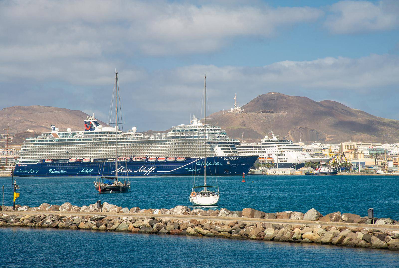 February 04 2022-Picture of Las palmas Canary Island port with particular ships for agreement.In the foreground some tourists are sailing back from the sea, in the background a huge clamming ship