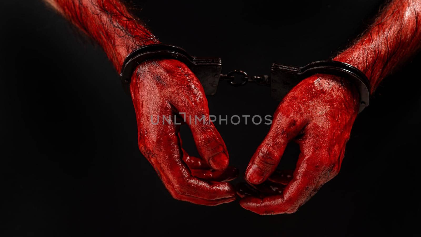 Close-up of male bloody handcuffed hands on a black background